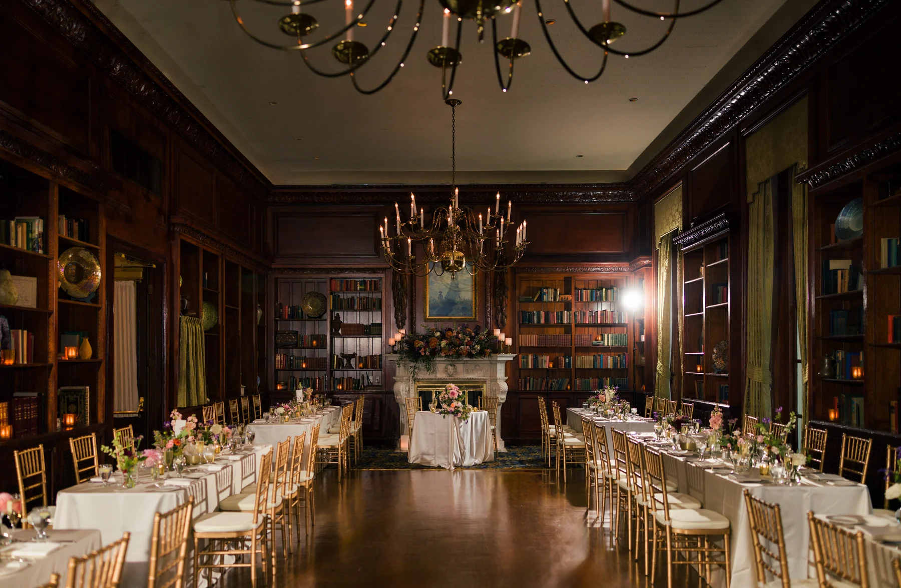 Elegant library reception hall at Hampshire House in Boston set with gold chiavari chairs, floral centerpieces and candlelit chandeliers.