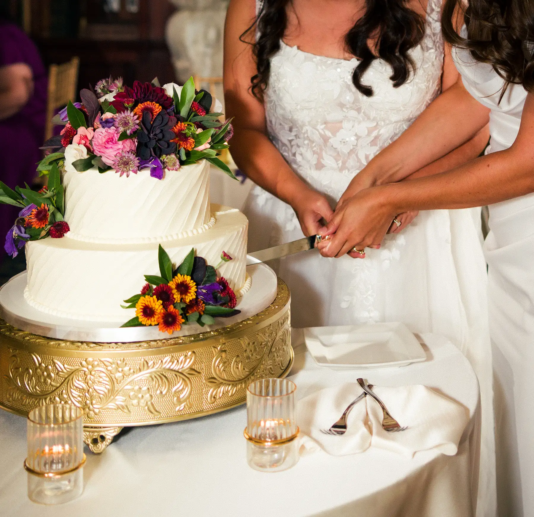 Brides Ashton Hattori and Stephanie Tillman cut their white floral wedding cake at Hampshire House in Boston.