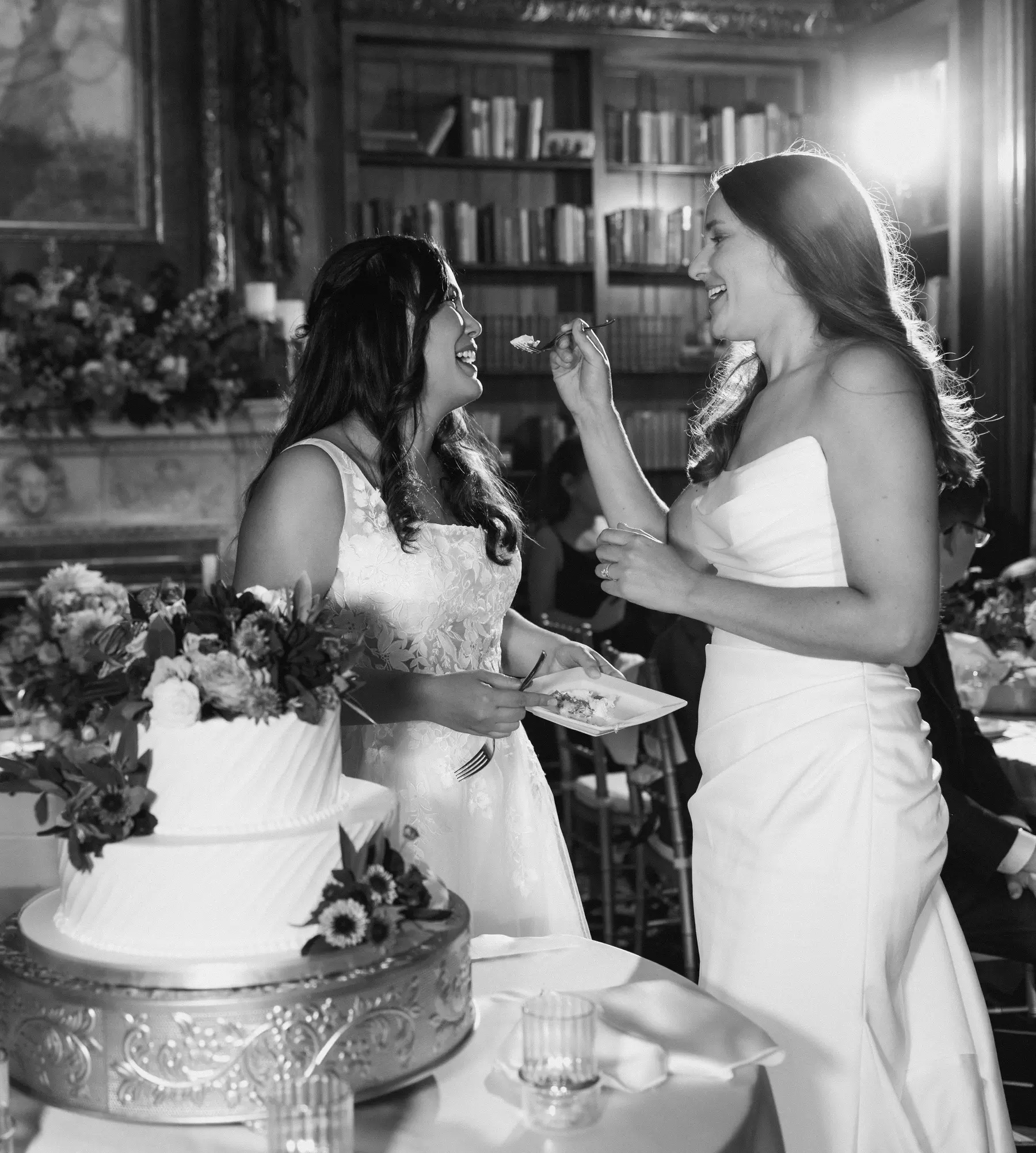 Ashton Hattori and Stephanie Tillman laugh while feeding each other wedding cake at Hampshire House in Boston.