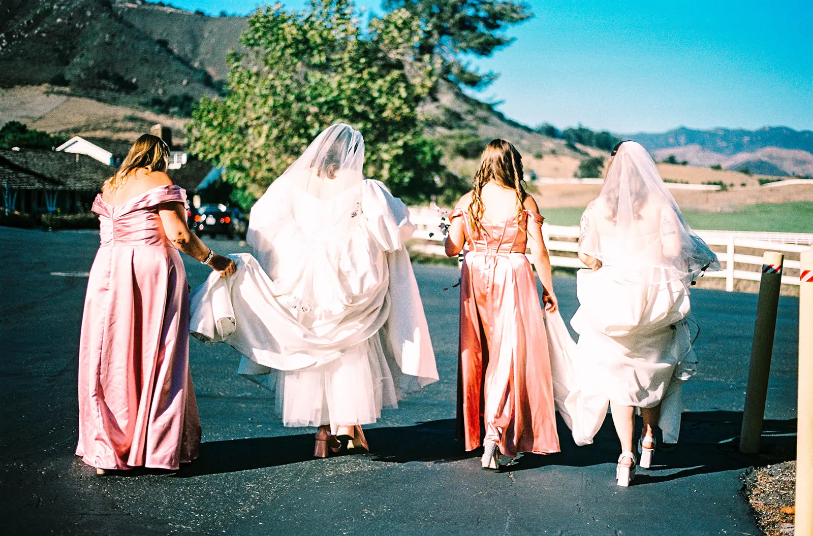 Brides Mimi and Courtney walk with bridesmaids in pink satin gowns at Madonna Inn in San Luis Obispo, Calif.