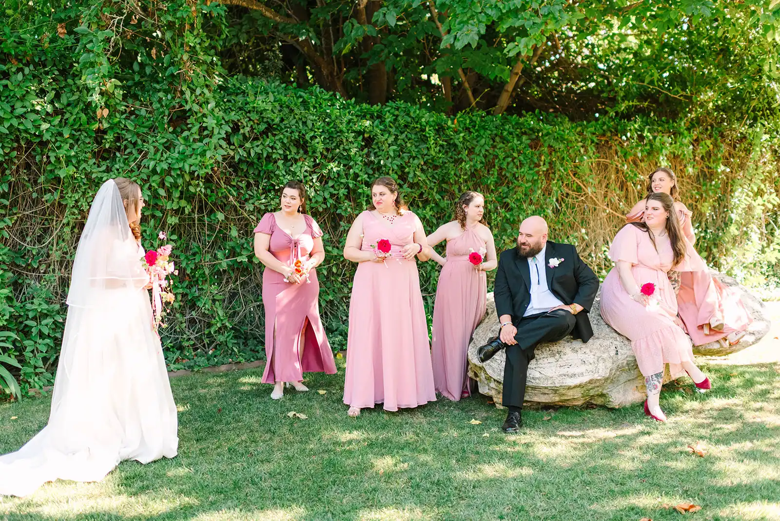 Bride Mimi faces her bridal party in pink dresses at Madonna Inn in San Luis Obispo, California.