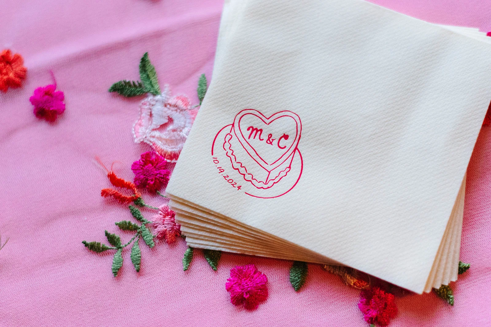 Custom cocktail napkins printed with 'M&C' inside a heart cake design for Mimi and Courtney's wedding on 10.19.2024.