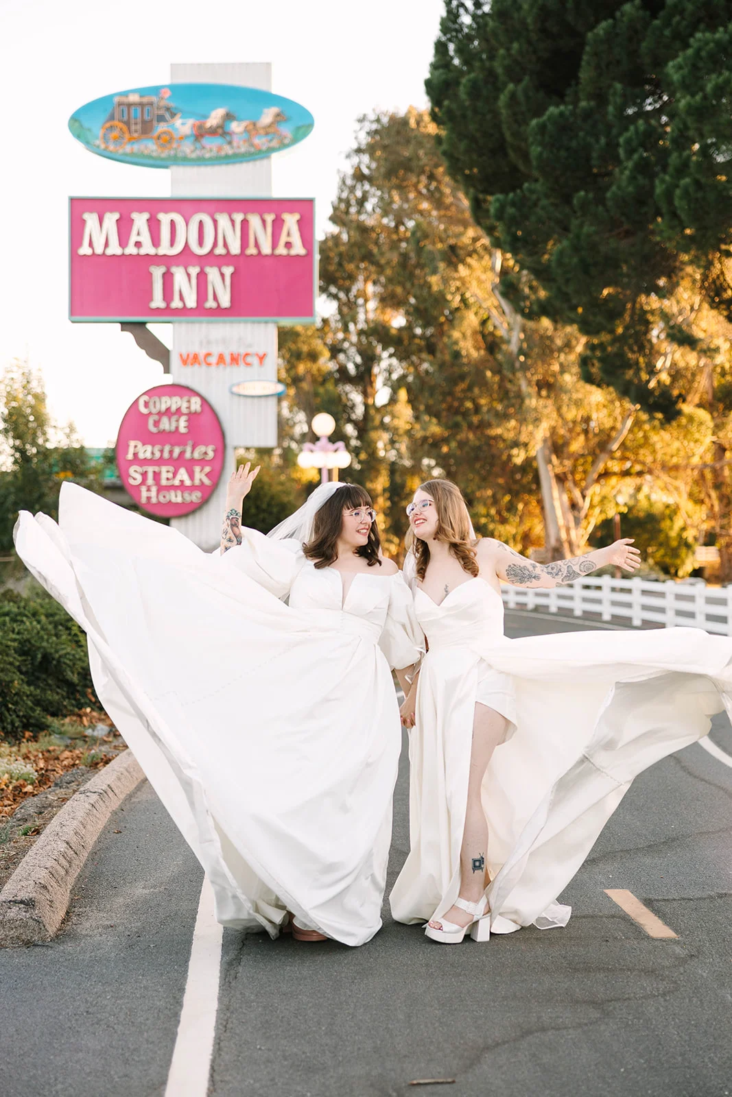 Brides Mimi and Courtney twirl their white wedding gowns in front of the Madonna Inn sign in San Luis Obispo, Calif.