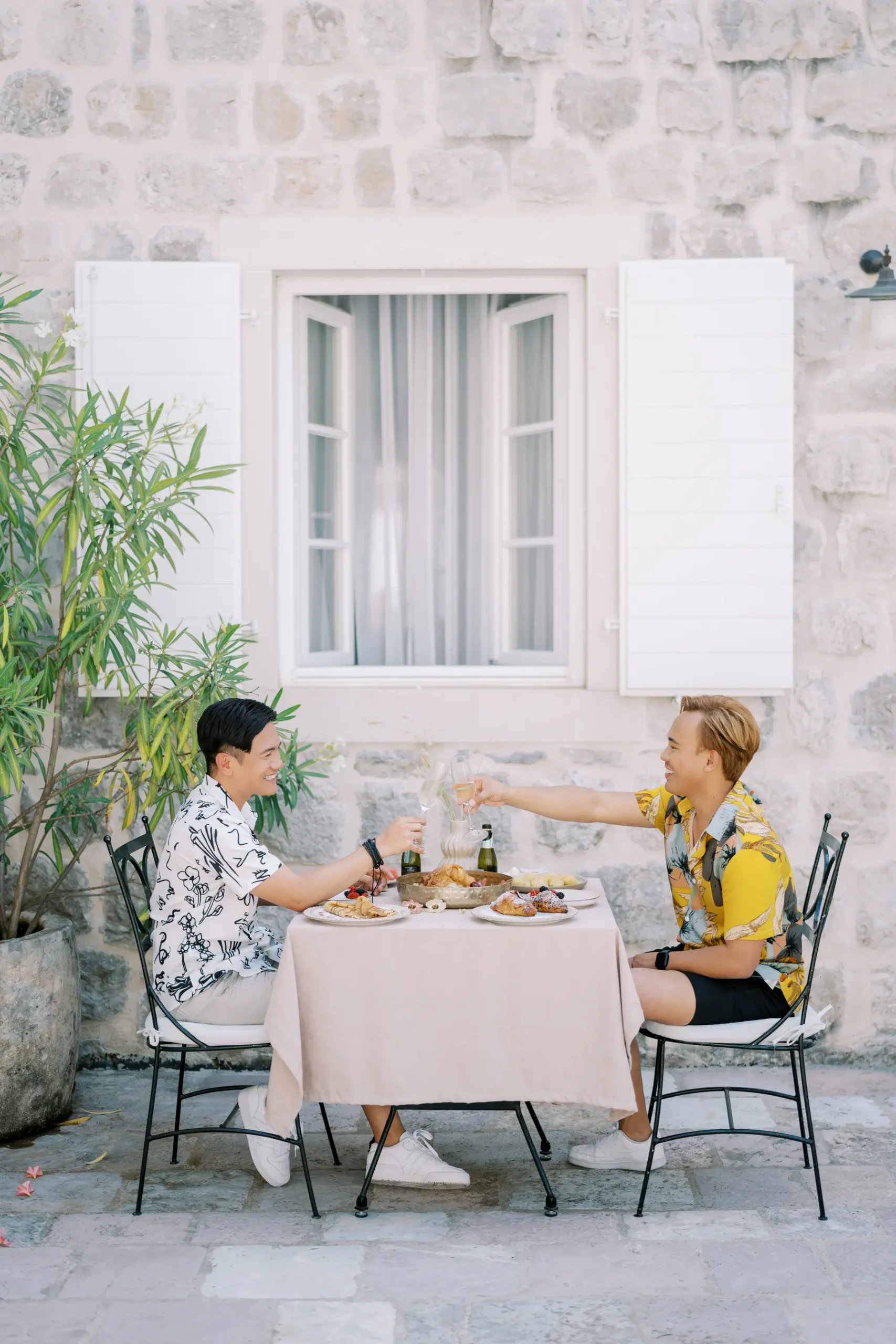 Ryan and Jori toast champagne at an outdoor table at Monte Bay Retreat in Perast, Montenegro.