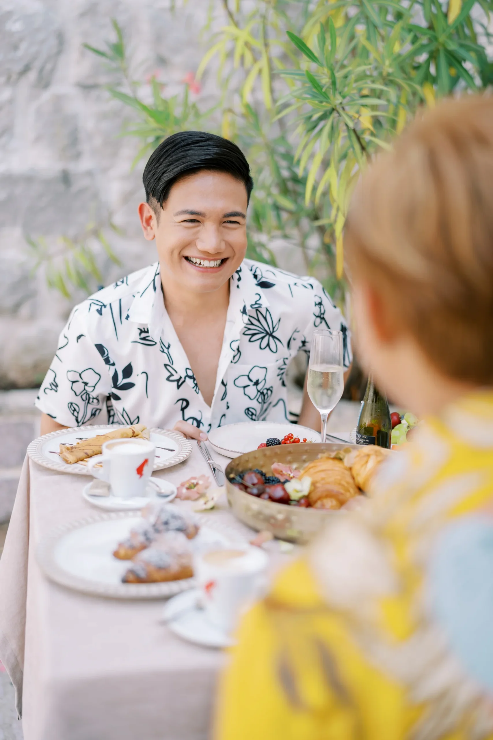 Ryan Jake Pisueña smiles joyfully at an outdoor brunch table at Monte Bay Retreat in Perast, Montenegro.