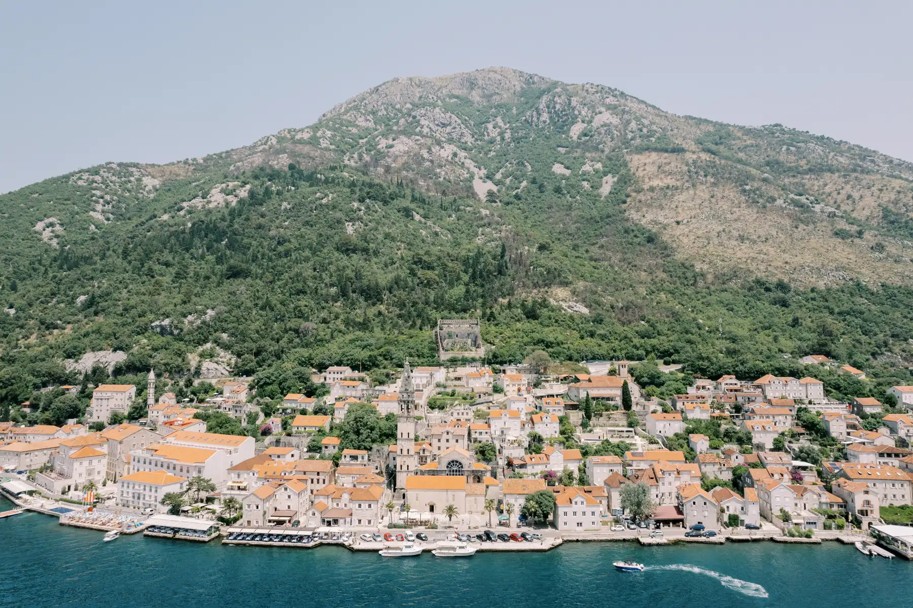 Aerial view of Perast, Montenegro, with terracotta-roofed stone buildings along the Bay of Kotor at Monte Bay Retreat.