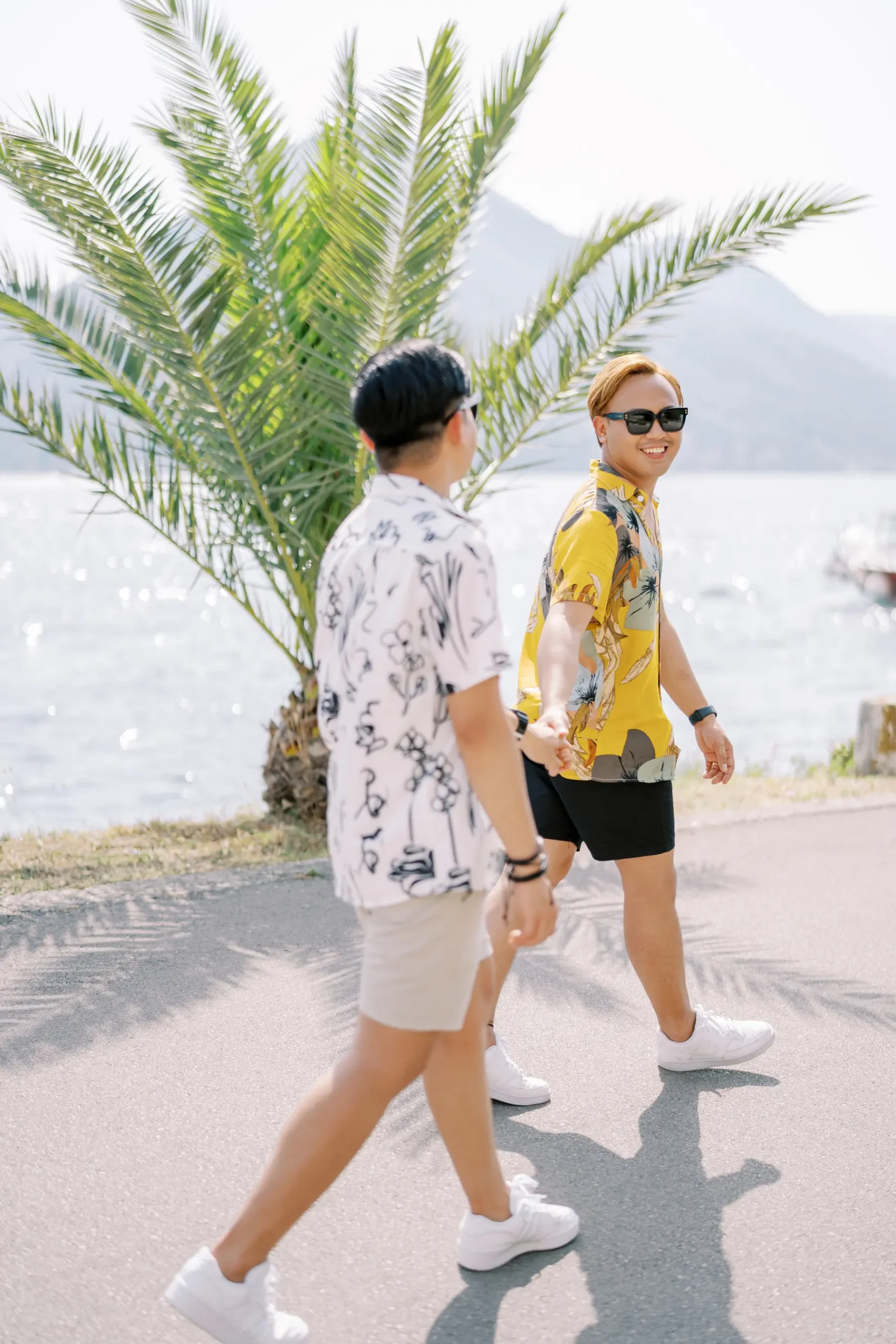 Ryan Jake and Jori hold hands walking along the waterfront at Monte Bay Retreat in Perast, Montenegro.