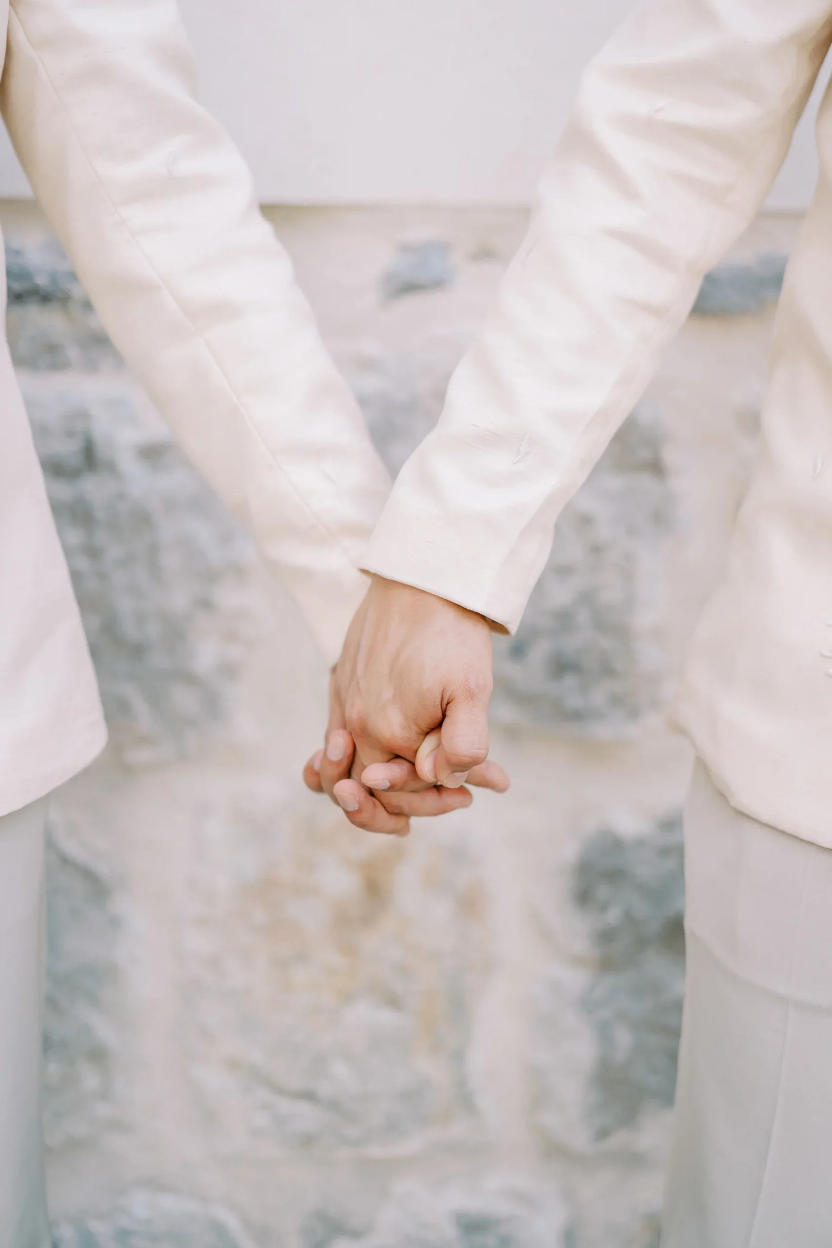 Ryan Jake Pisueña and Jori Blas Lazalita hold hands in white suits at Monte Bay Retreat in Perast, Montenegro.