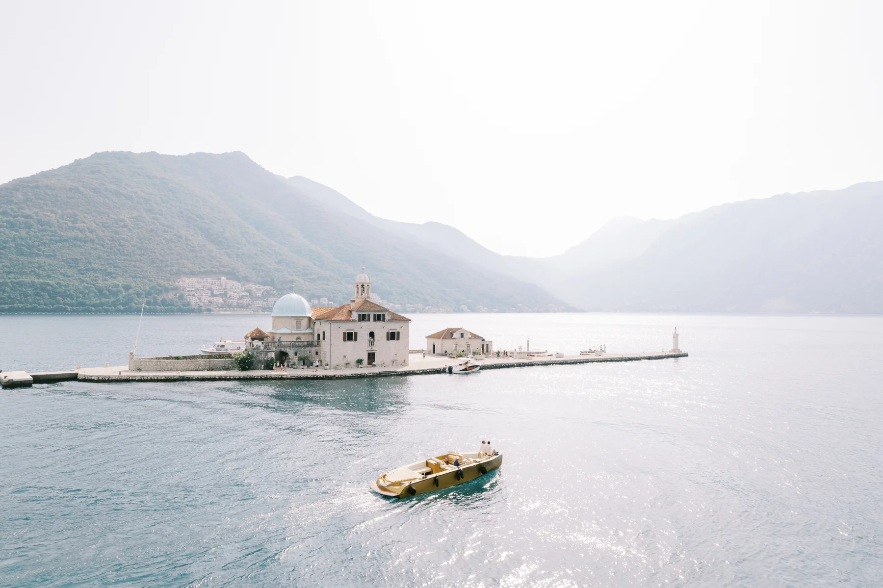A golden boat glides past Our Lady of the Rocks island church in Perast, Montenegro, during Ryan and Jori's wedding.
