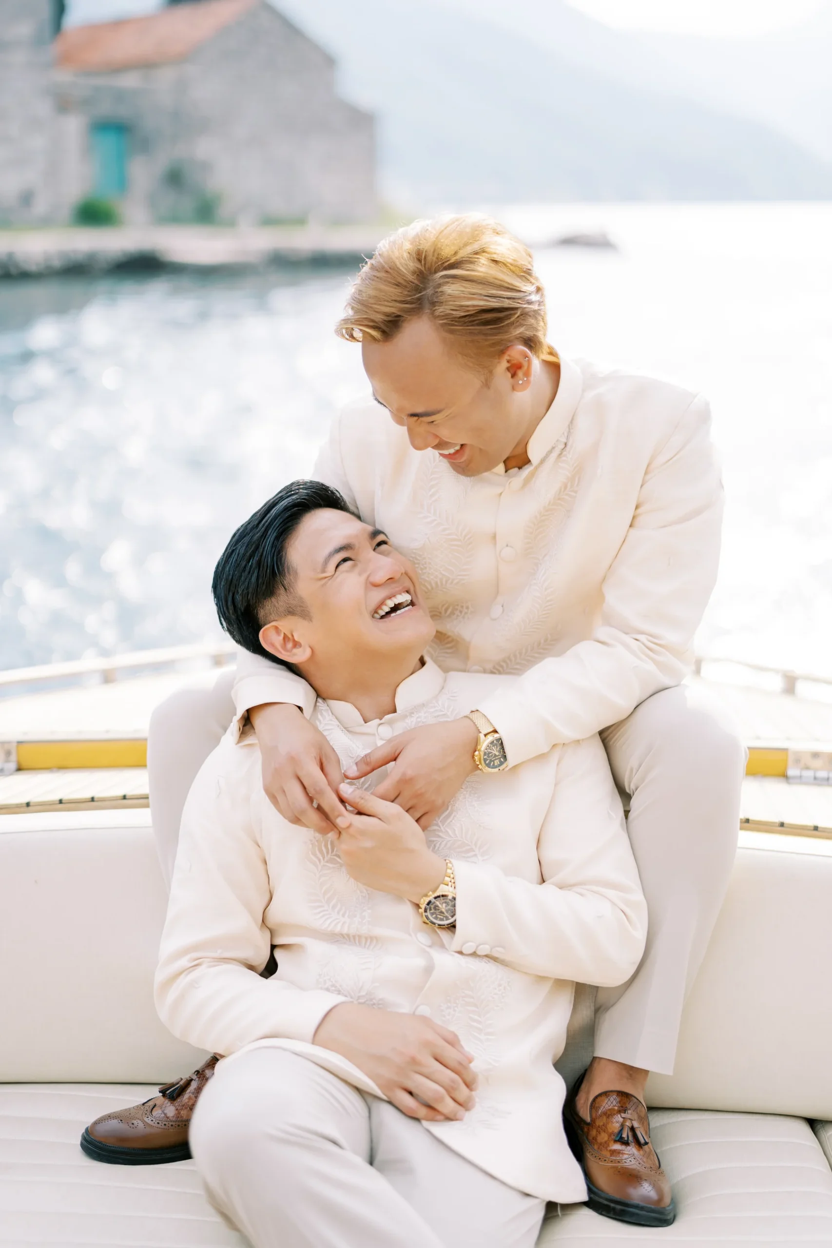Ryan Jake and Jori laugh joyfully together in matching cream barong suits aboard a boat in Perast, Montenegro.