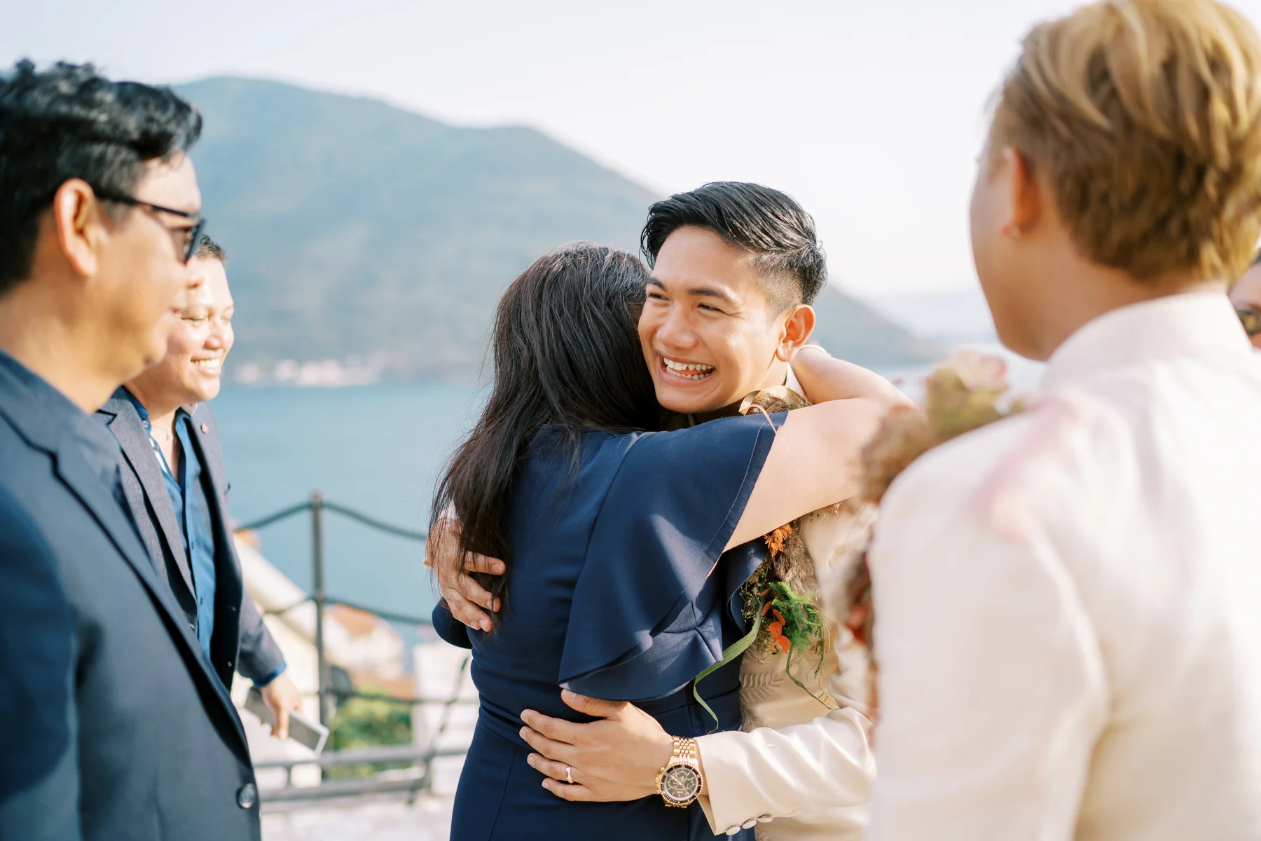 Ryan Jake Pisueña laughs while hugging a guest in a navy dress at Monte Bay Retreat in Perast, Montenegro.
