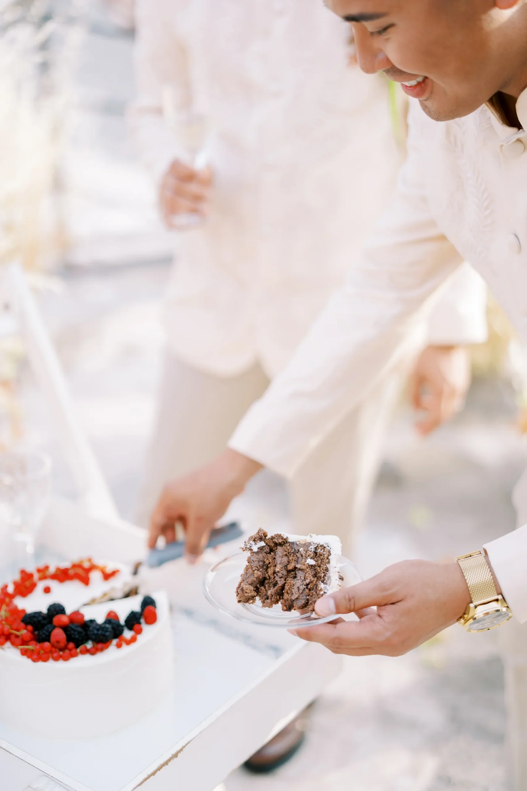Ryan Jake Pisueña smiles while cutting a chocolate wedding cake decorated with fresh berries at Monte Bay Retreat in Perast, Montenegro.