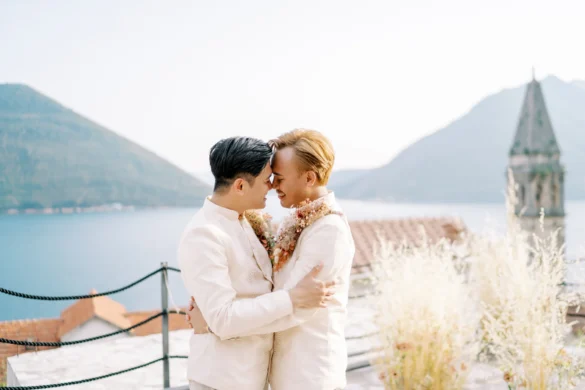 Ryan Jake and Jori embrace forehead-to-forehead in white suits at Monte Bay Retreat in Perast, Montenegro.