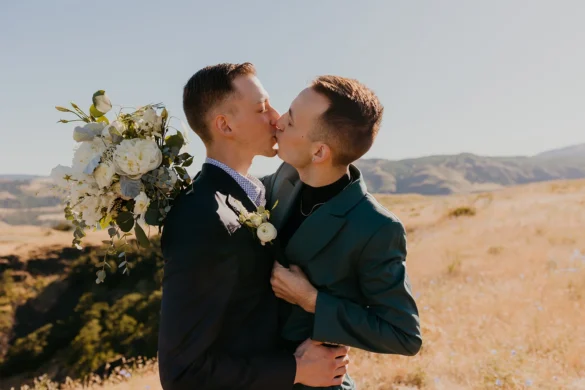 Ben and Nolan share a first kiss holding a white floral bouquet at Mayer State Park in Mosier, OR.