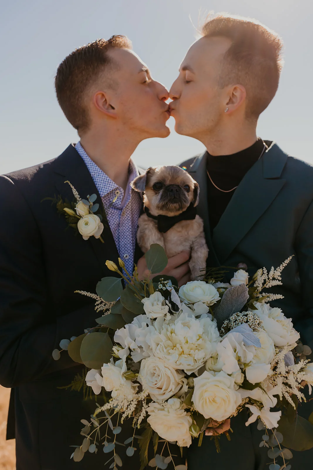 Ben and Nolan share a kiss while holding their pug in a bow tie at Mayer State Park in Mosier, OR.