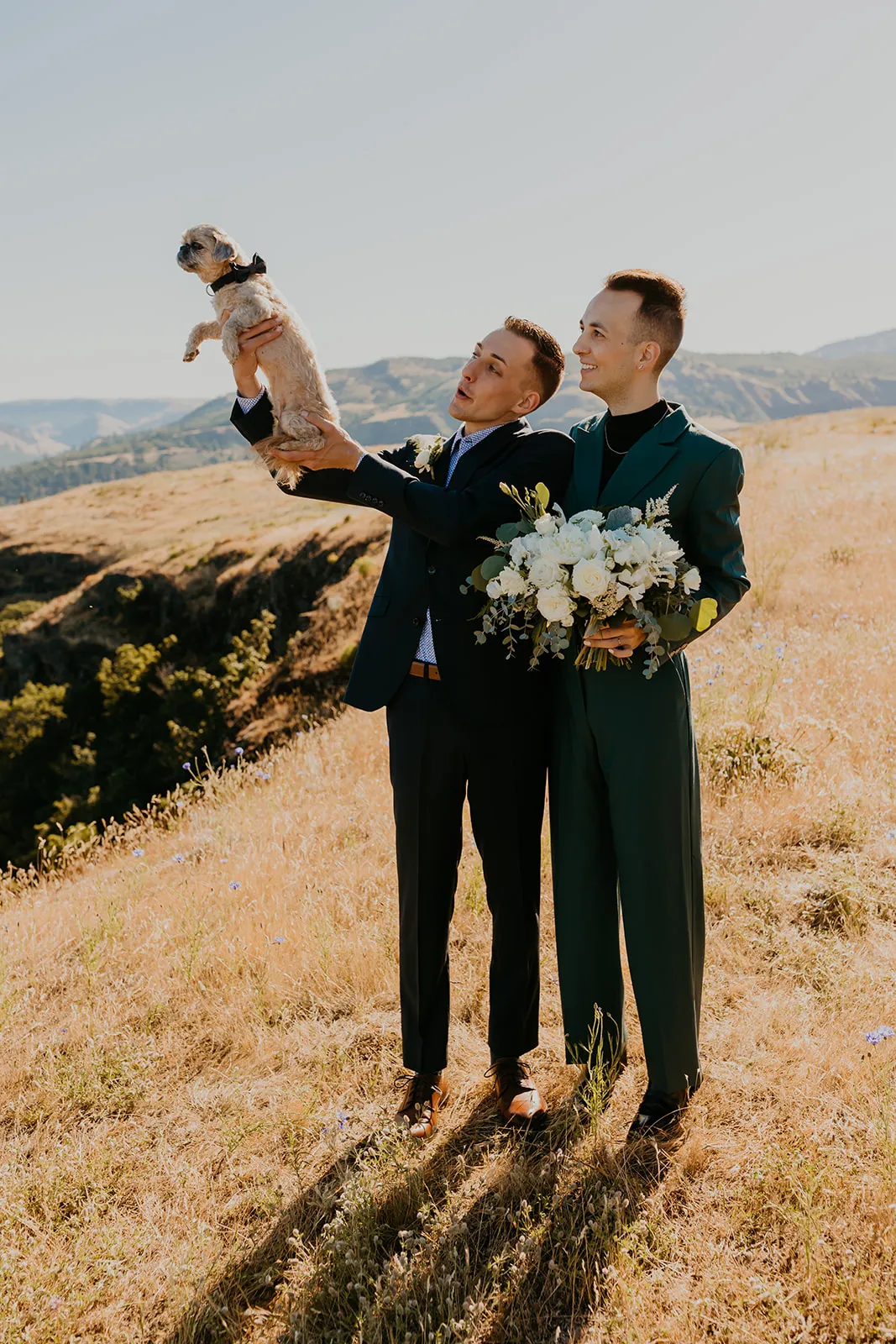 Ben and Nolan hold their small dog aloft during couple portraits at Mayer State Park in Mosier, Oregon.