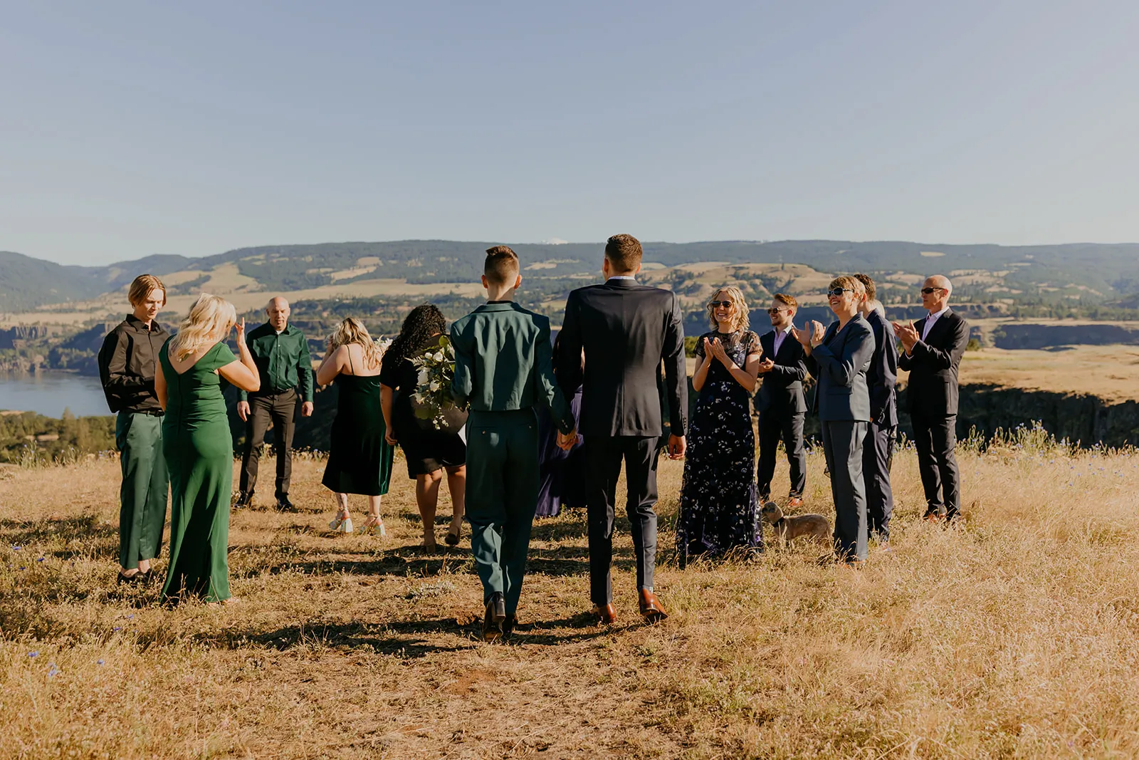 Ben and Nolan walk hand-in-hand toward cheering guests at Mayer State Park in Mosier, OR.