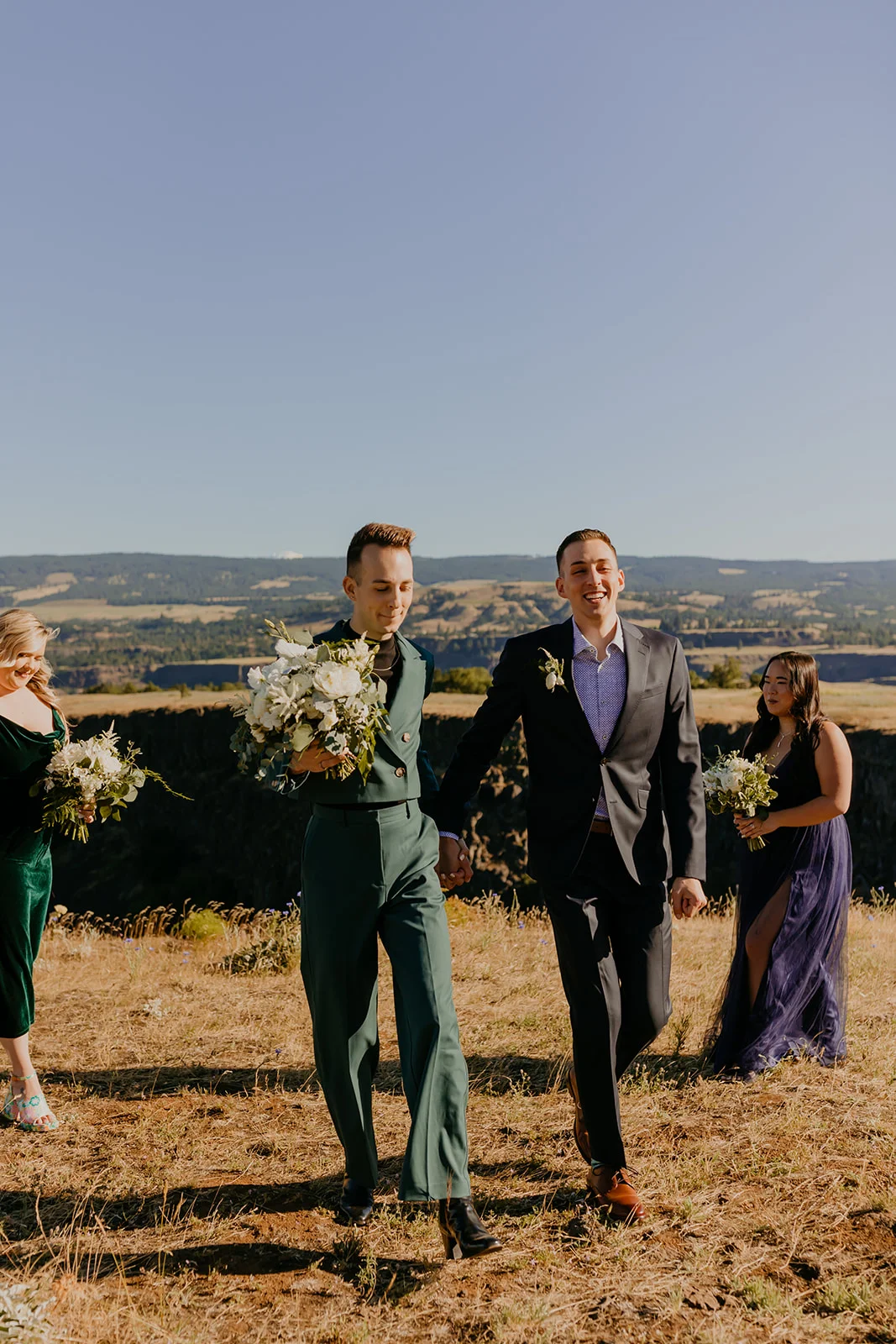 Grooms Ben and Nolan walk hand in hand at Mayer State Park in Mosier, OR, flanked by their wedding party.
