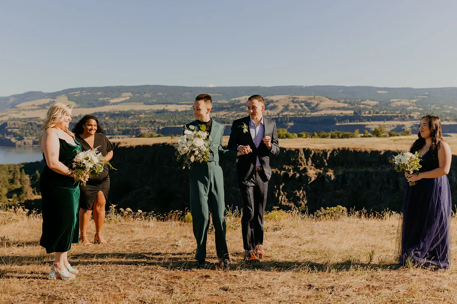 Ben and Nolan share a joyful moment with their wedding party on a cliff overlooking the Columbia River Gorge at Mayer State Park.