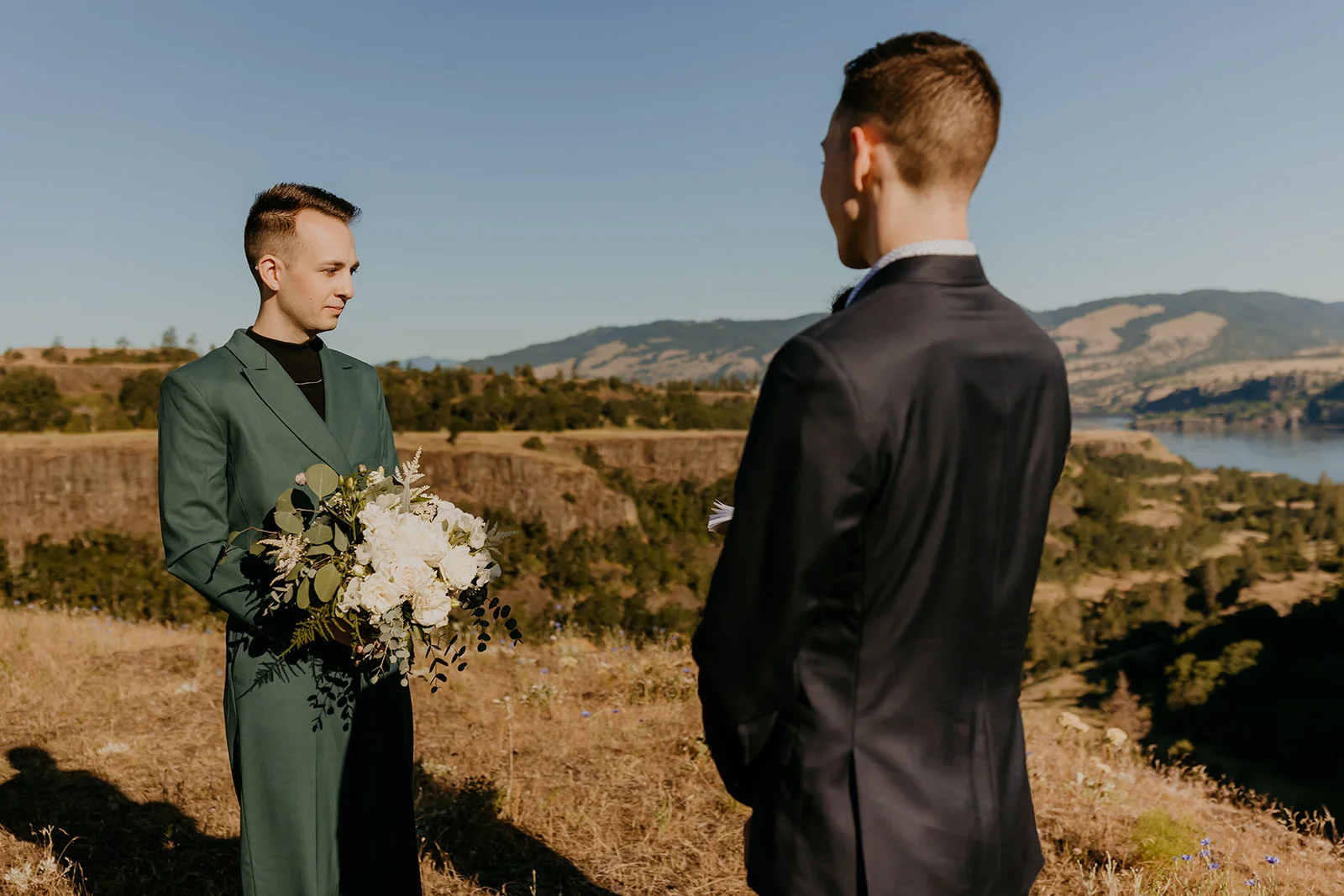 Ben and Nolan face each other during their ceremony at Mayer State Park in Mosier, OR, with the Columbia River Gorge behind them.