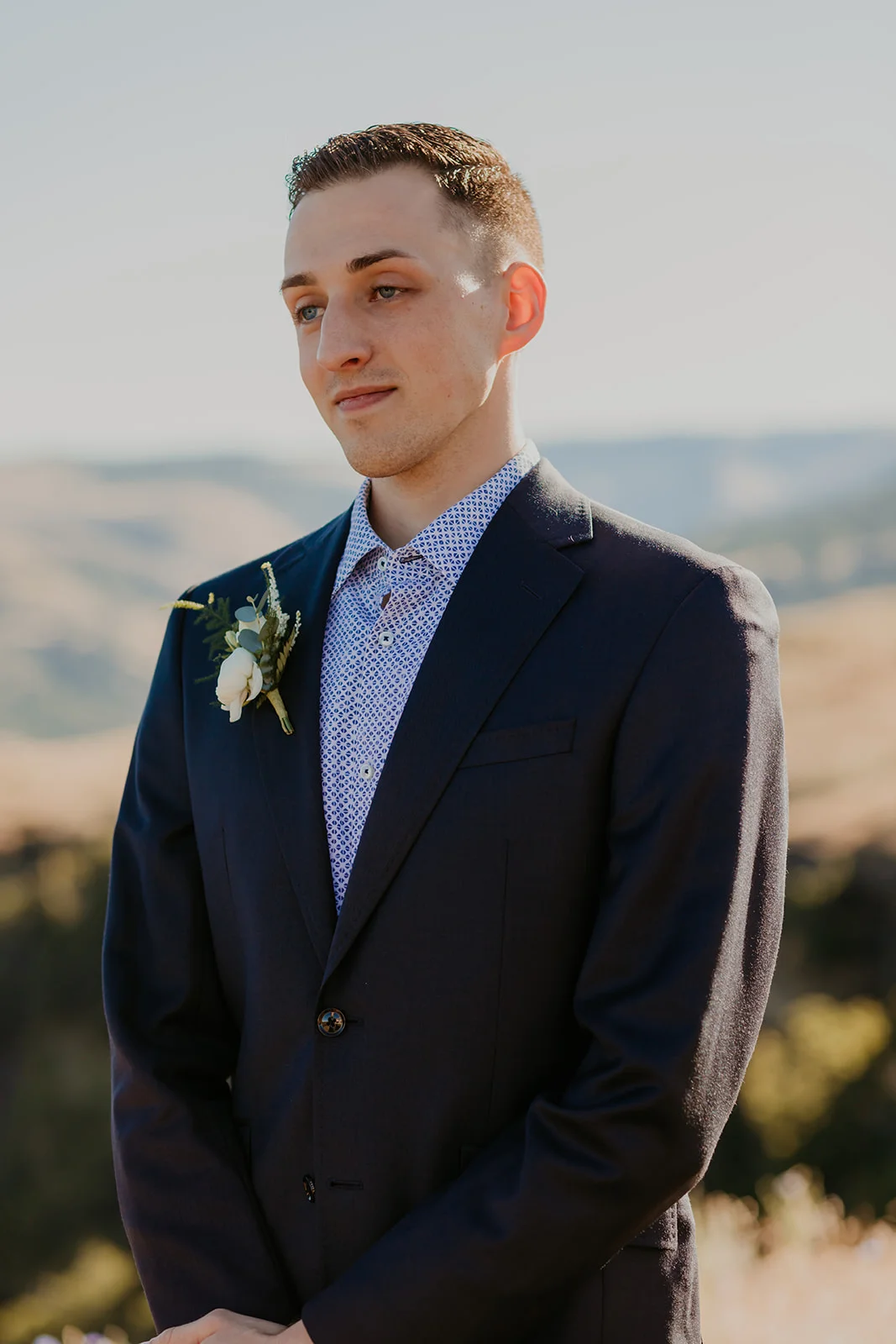 Nolan stands in a navy suit with a white rose boutonniere at Mayer State Park in Mosier, OR.