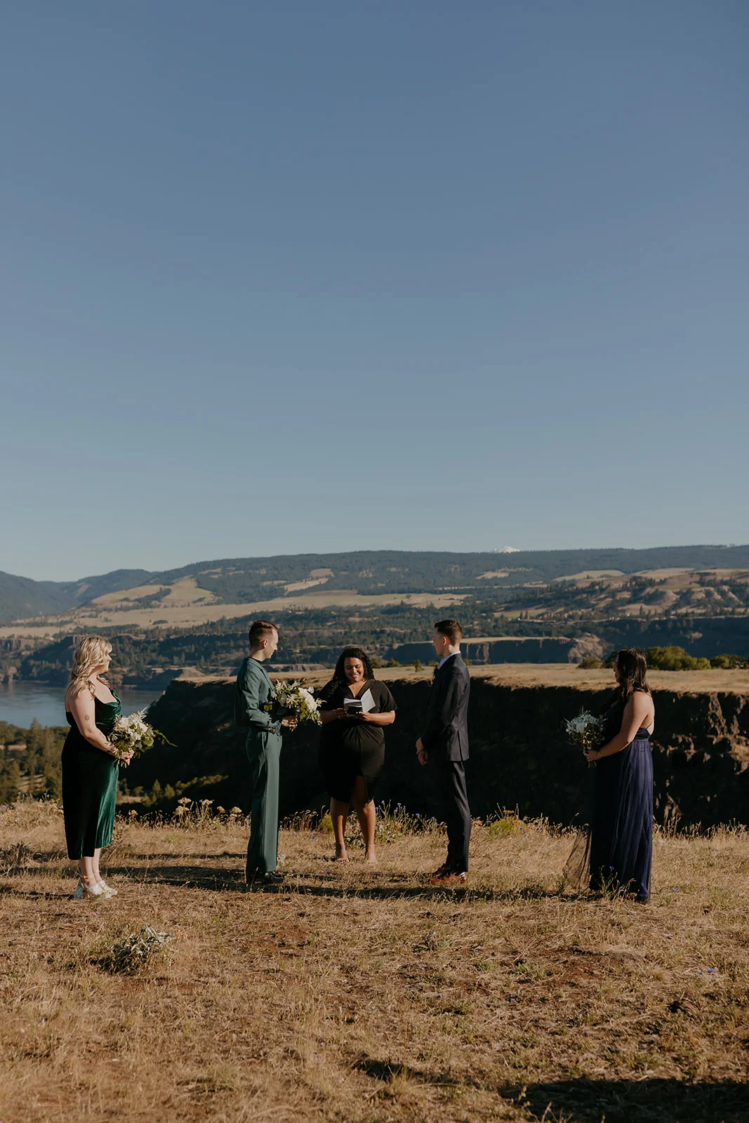 Ben and Nolan exchange vows with their wedding party at Mayer State Park in Mosier, Oregon, overlooking the Columbia River Gorge.