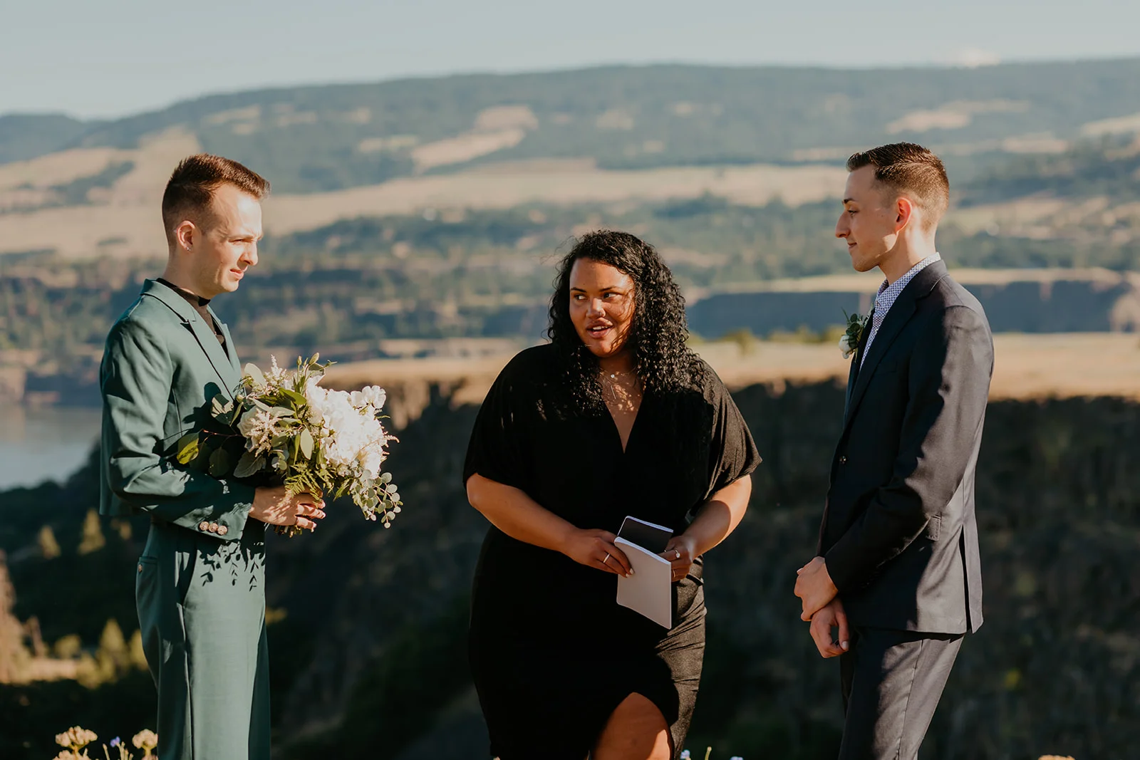 Ben and Nolan stand with their officiant during their outdoor elopement ceremony at Mayer State Park in Mosier, OR.