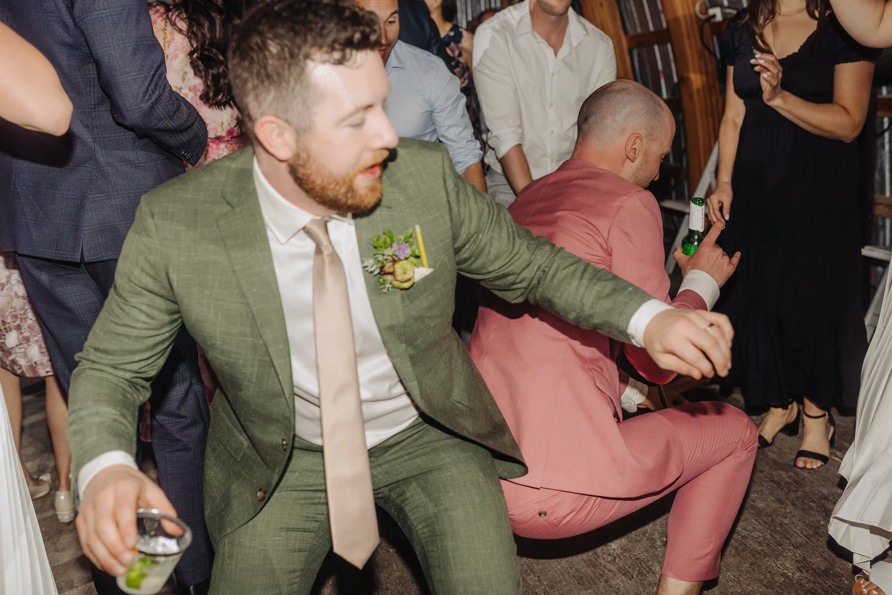 Guests in green and pink suits dance energetically at Trent and Cameron Harris-McCoy's wedding at The Hillside Lodge in Golden, BC.
