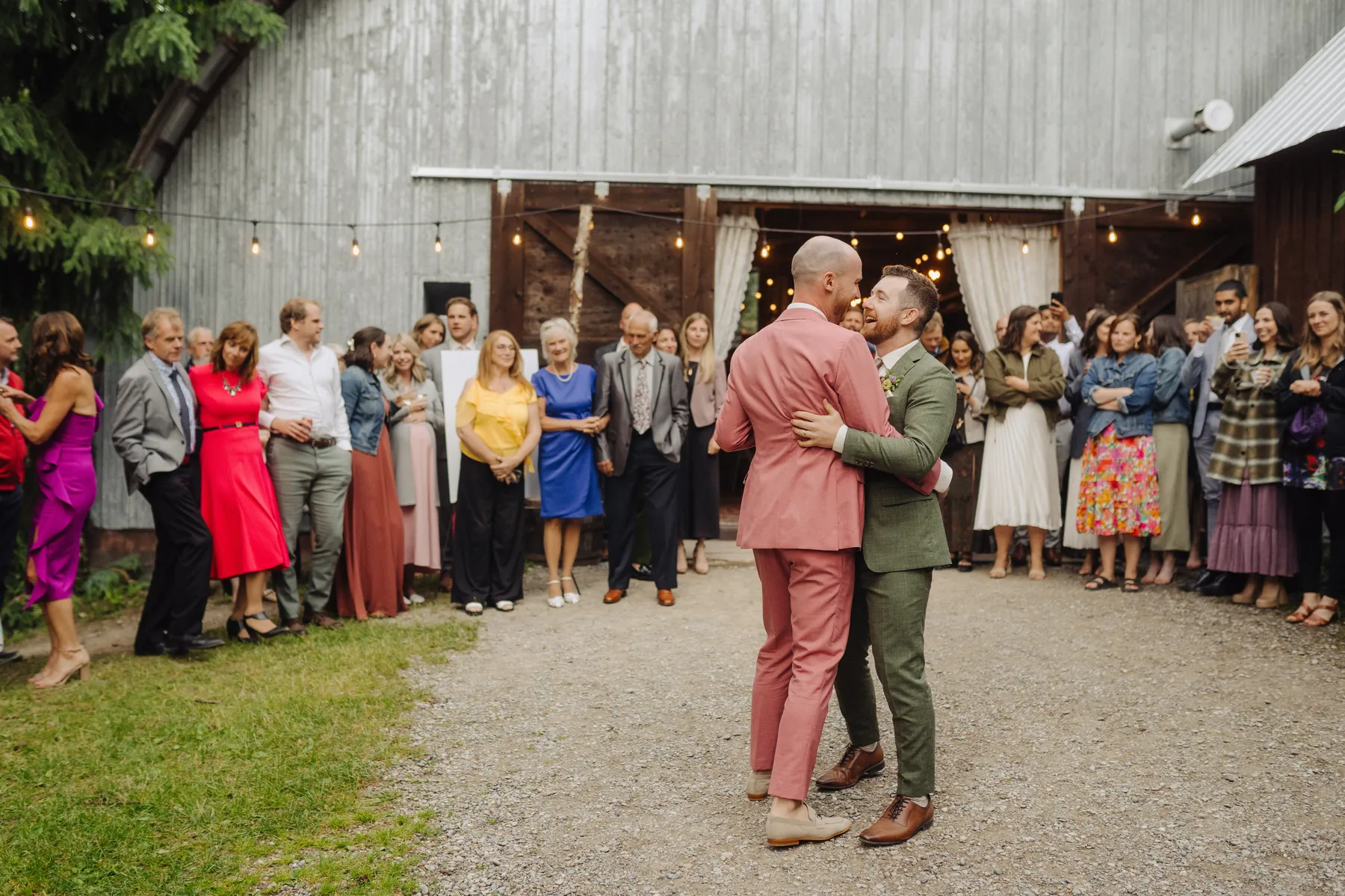 Trent and Cameron Harris-McCoy share their first dance outside The Hillside Lodge & Chalets in Golden, BC, as guests look on.