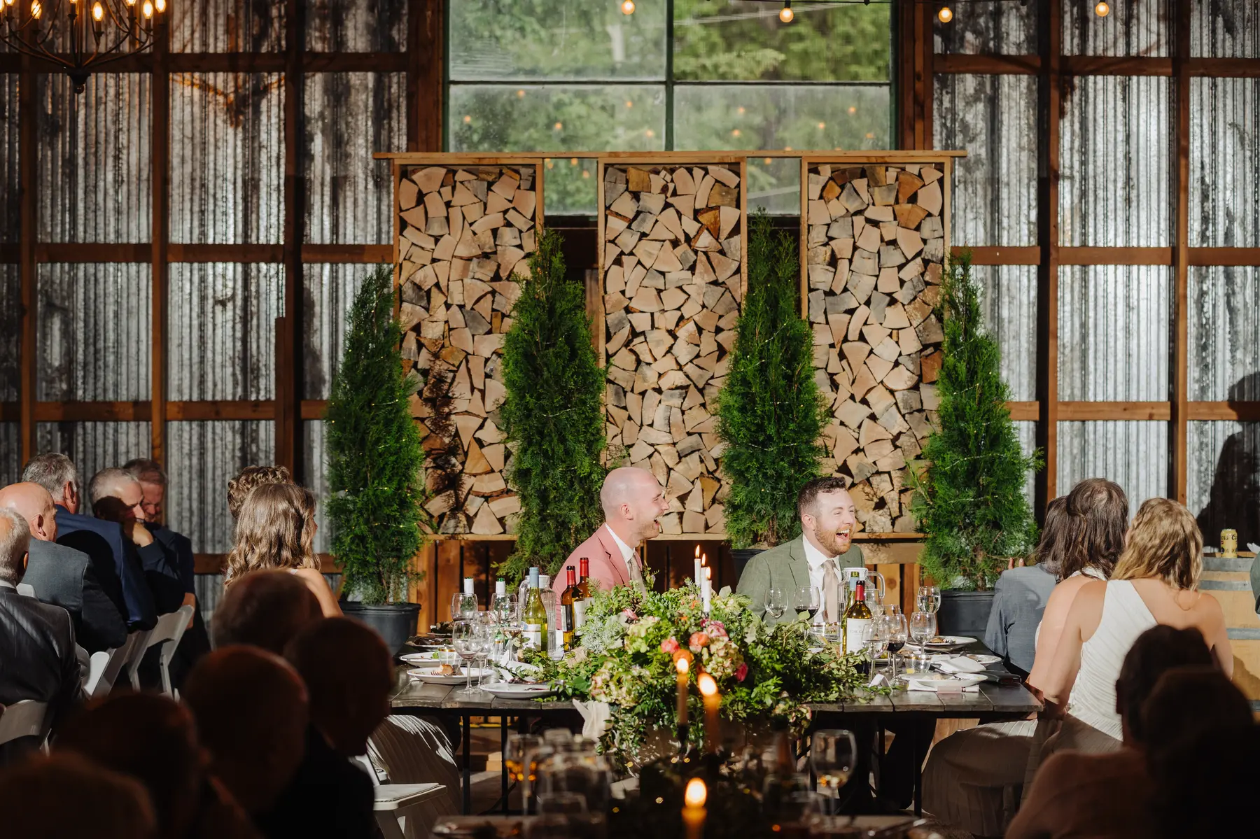 Trent and Cameron Harris-McCoy laugh together at their rustic reception head table at The Hillside Lodge in Golden, BC.