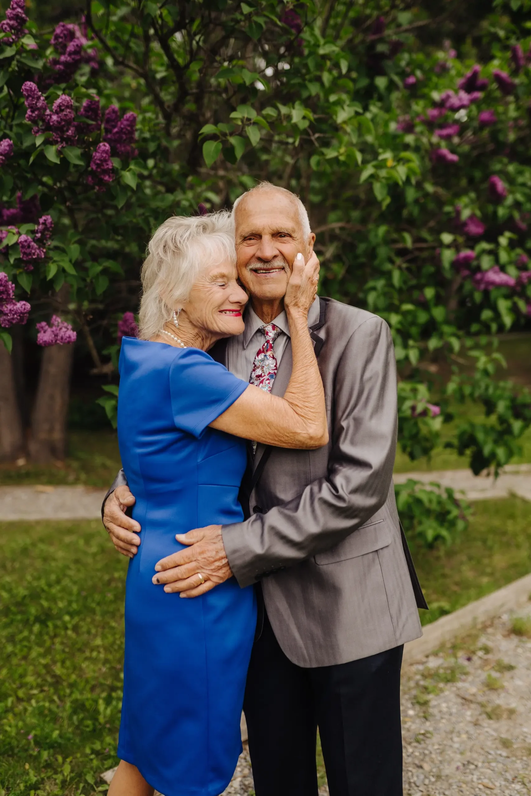 An elderly couple embraces among blooming lilacs at The Hillside Lodge & Chalets in Golden, BC, Canada.