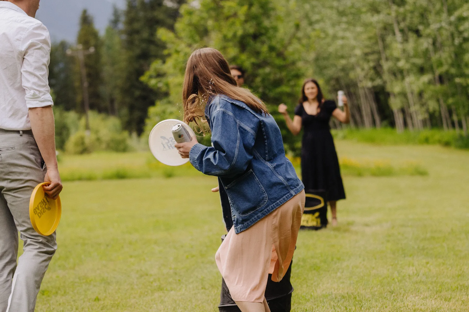 Wedding guests play frisbee on a lush green lawn at The Hillside Lodge & Chalets in Golden, BC, Canada.