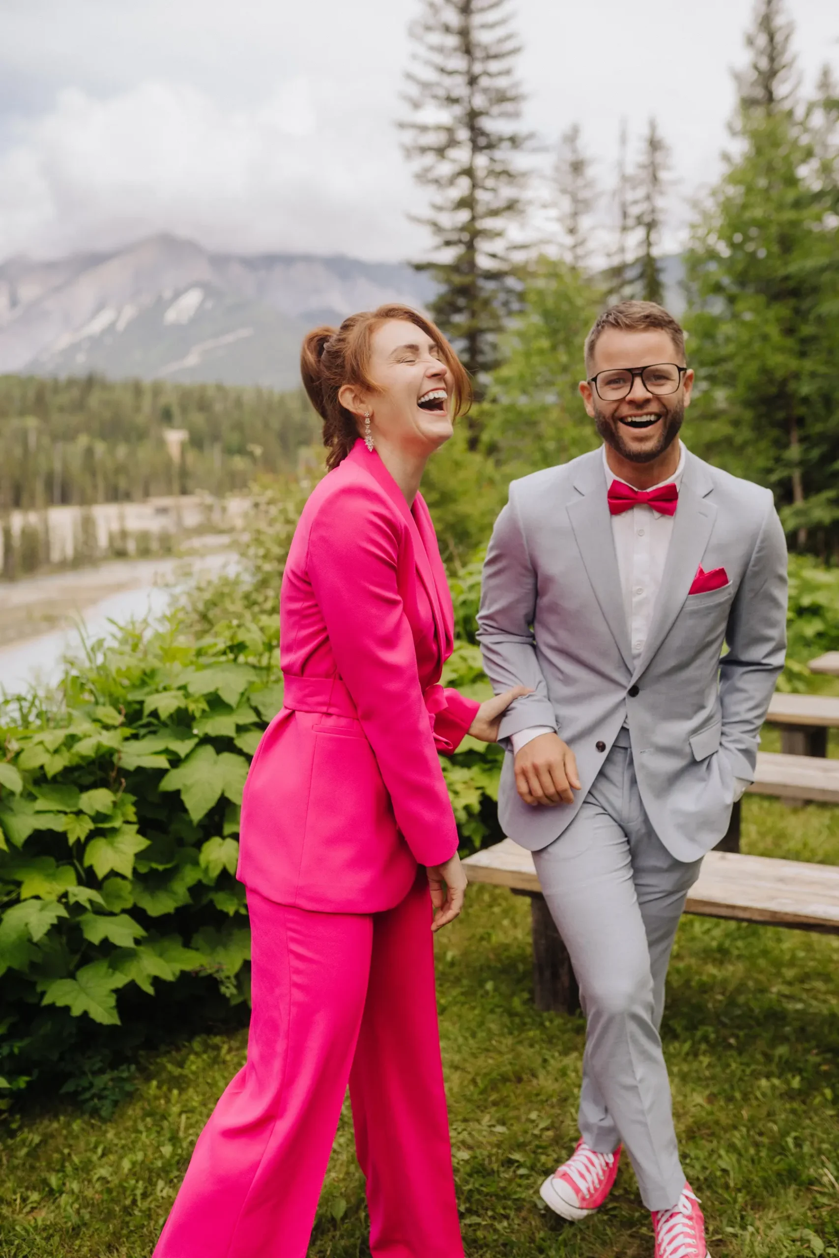 Trent and Cameron Harris-McCoy laugh together in coordinating pink and gray suits at The Hillside Lodge & Chalets in Golden, BC.