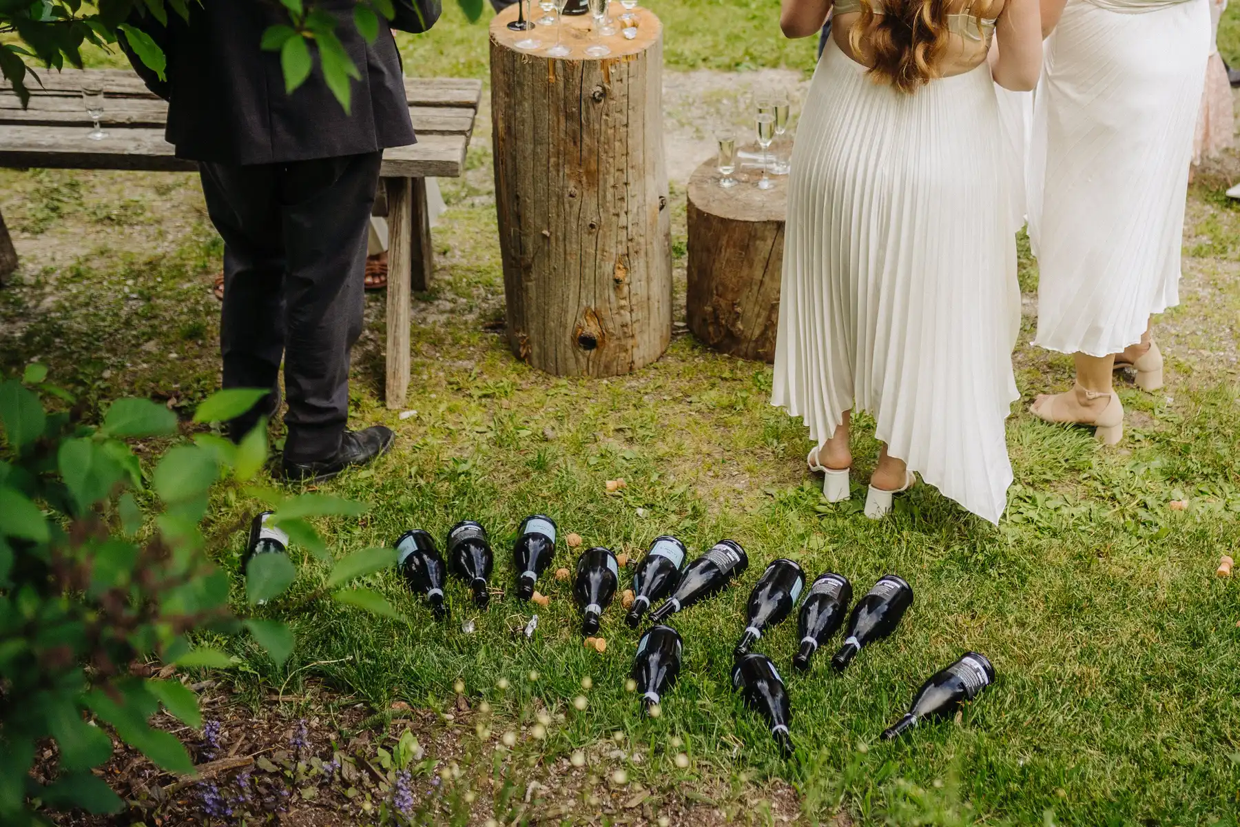 Empty champagne bottles on grass at The Hillside Lodge & Chalets in Golden, BC, during Trent and Cameron Harris-McCoy's wedding reception.
