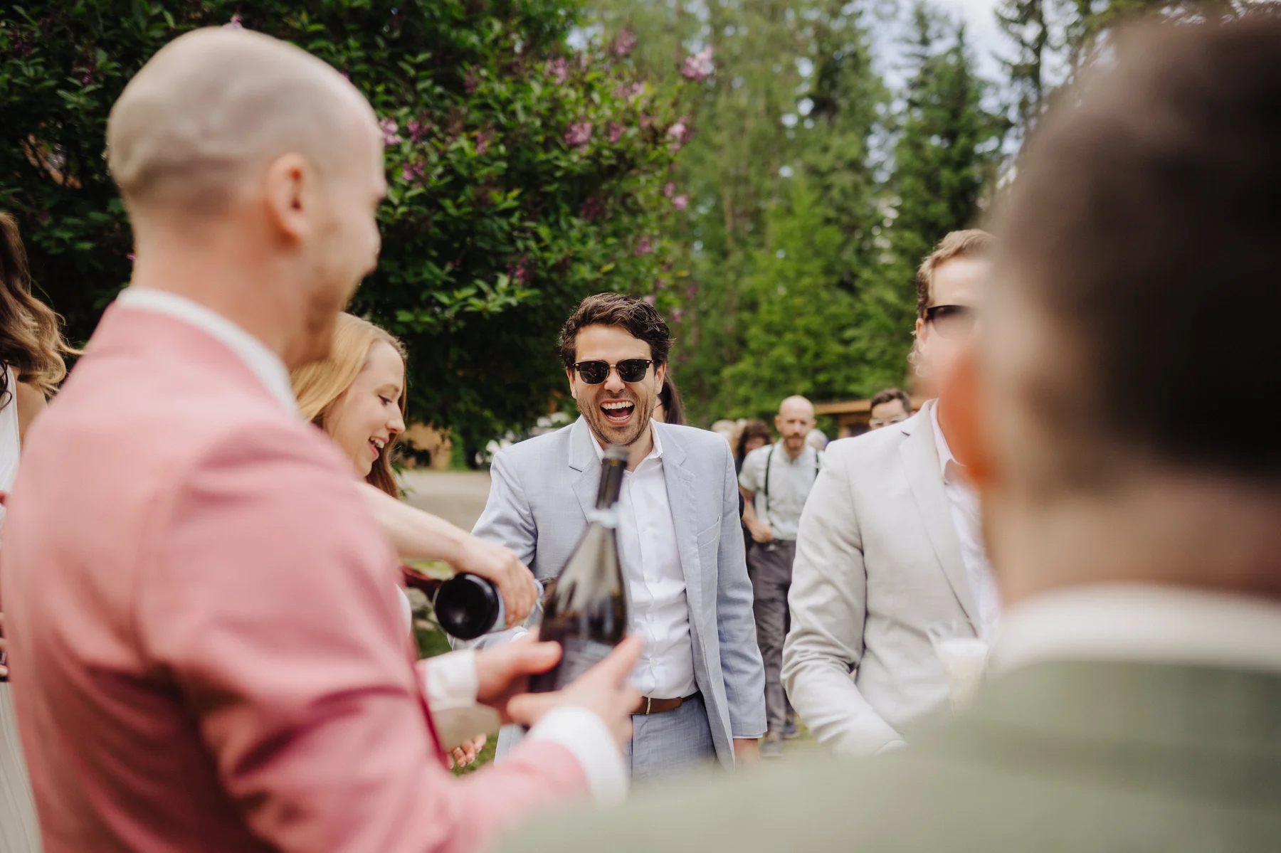 Wedding guests laugh and pour wine outdoors at The Hillside Lodge & Chalets in Golden, BC, Canada.