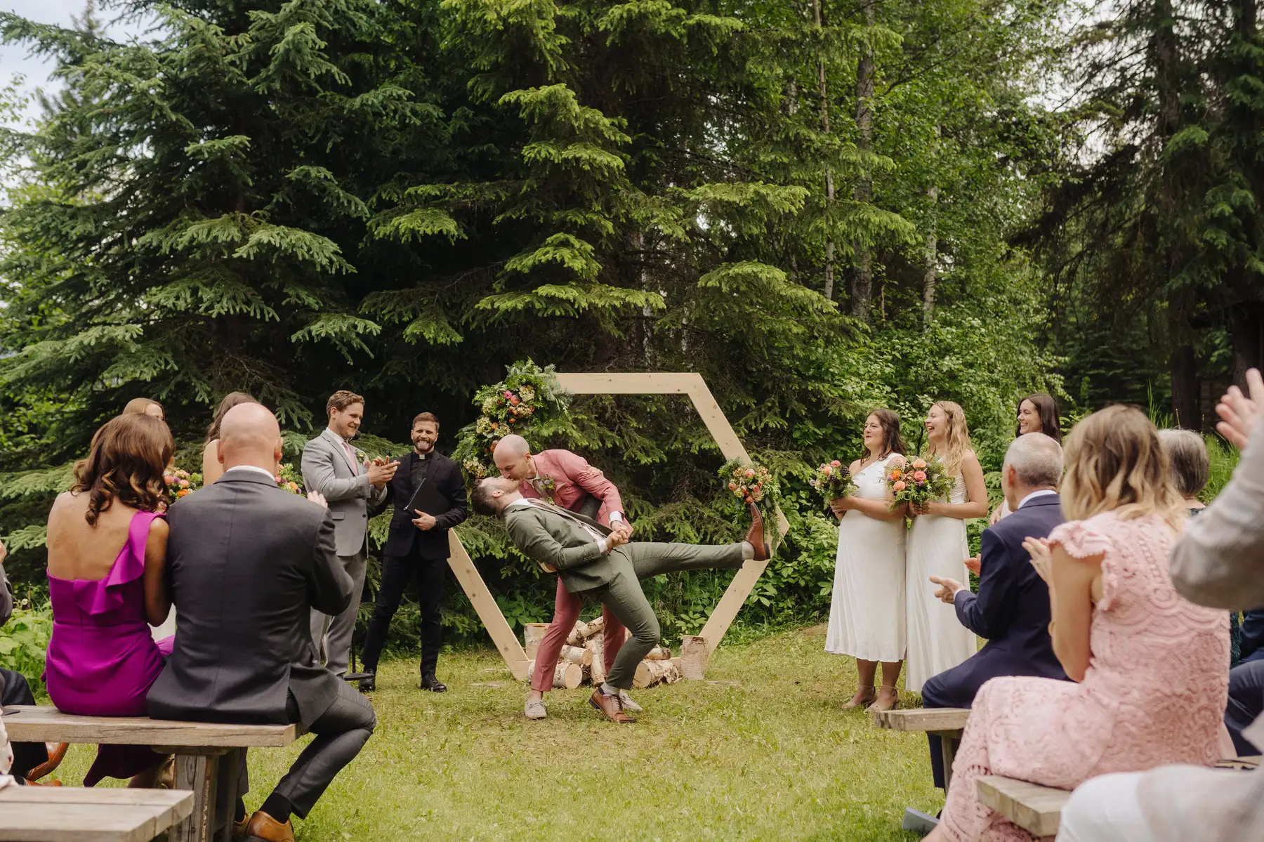 Trent and Cameron Harris-McCoy share a dramatic dip kiss at their outdoor wedding at The Hillside Lodge & Chalets in Golden, BC.