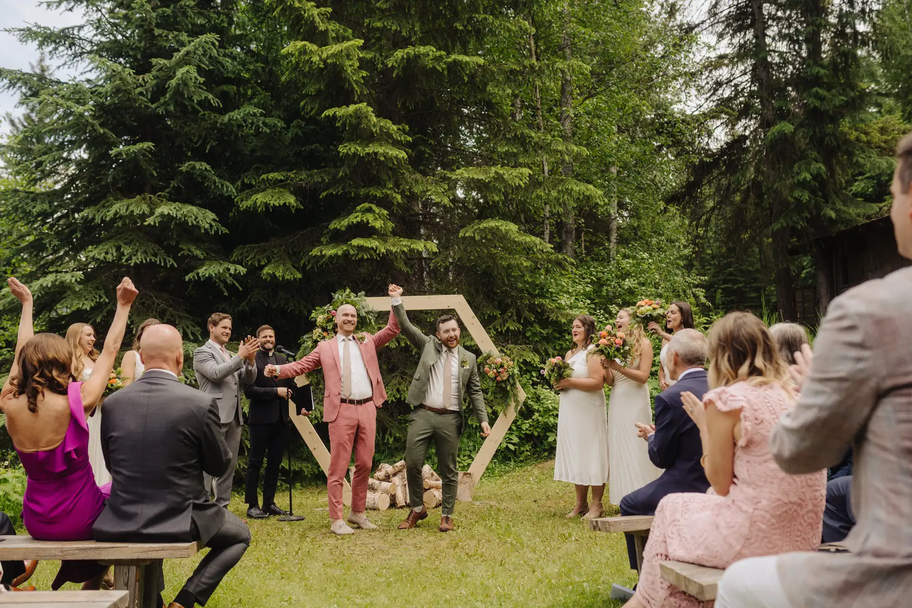 Trent and Cameron Harris-McCoy raise joined hands in celebration after their ceremony at The Hillside Lodge & Chalets in Golden, BC.