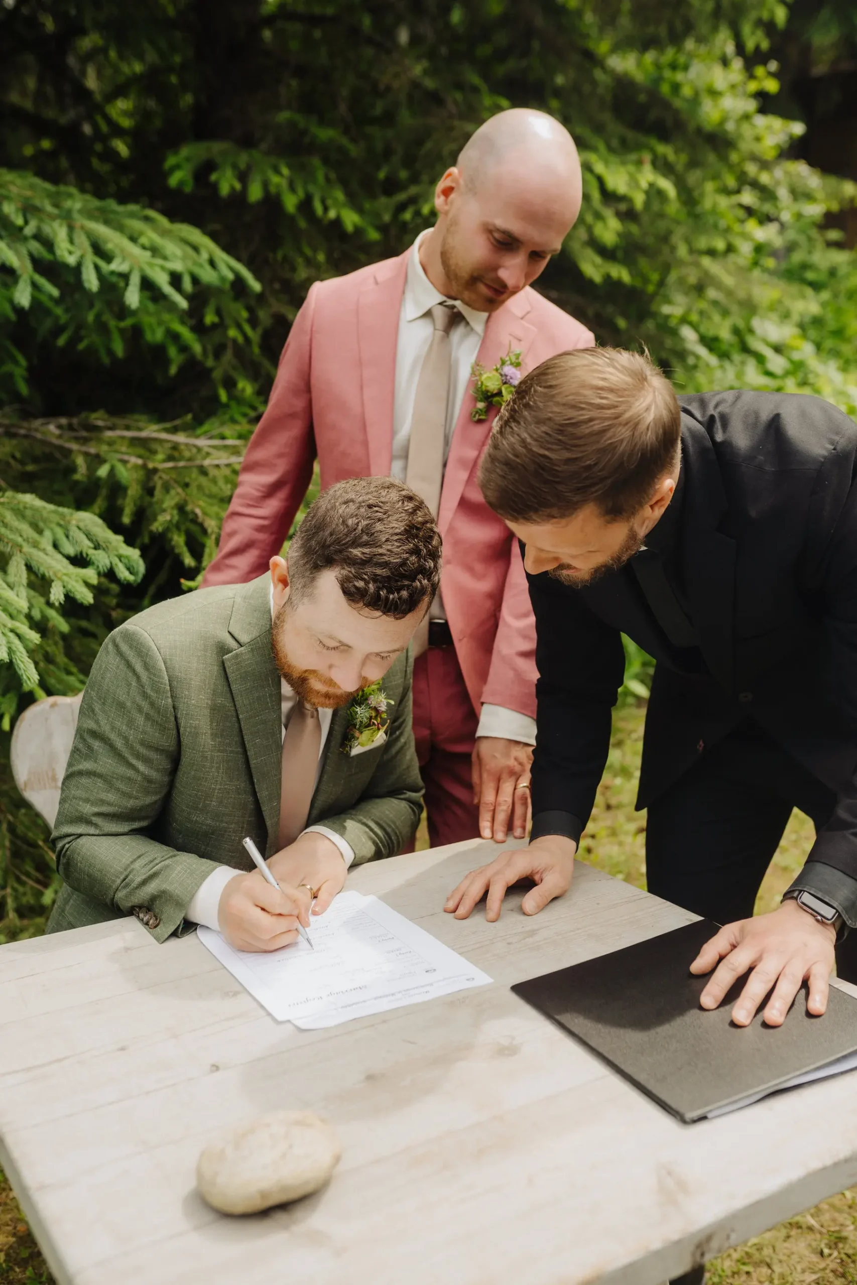 Groom Trent Harris-McCoy signs the marriage certificate outdoors at The Hillside Lodge & Chalets in Golden, BC.