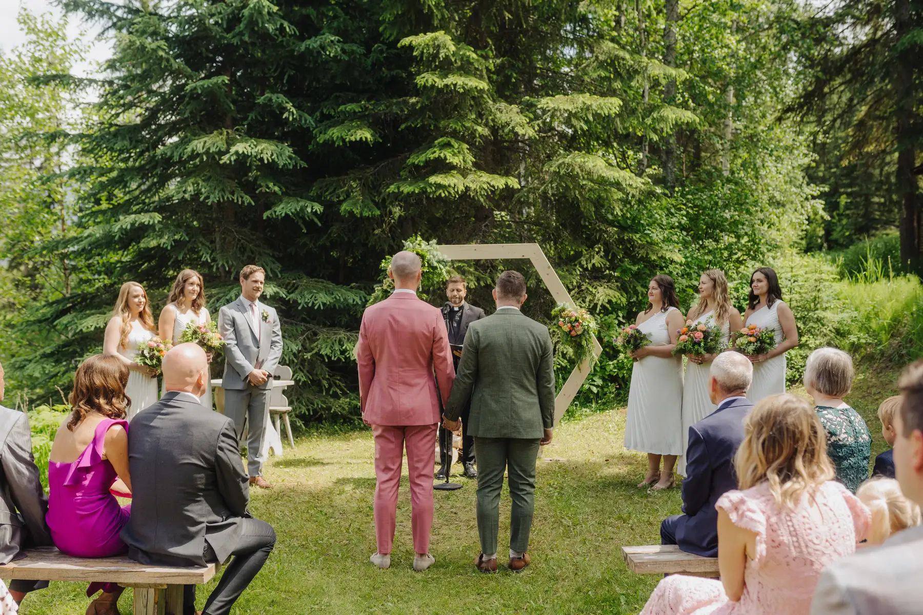 Trent and Cameron Harris-McCoy hold hands at the altar during their outdoor wedding ceremony at The Hillside Lodge & Chalets in Golden, BC.