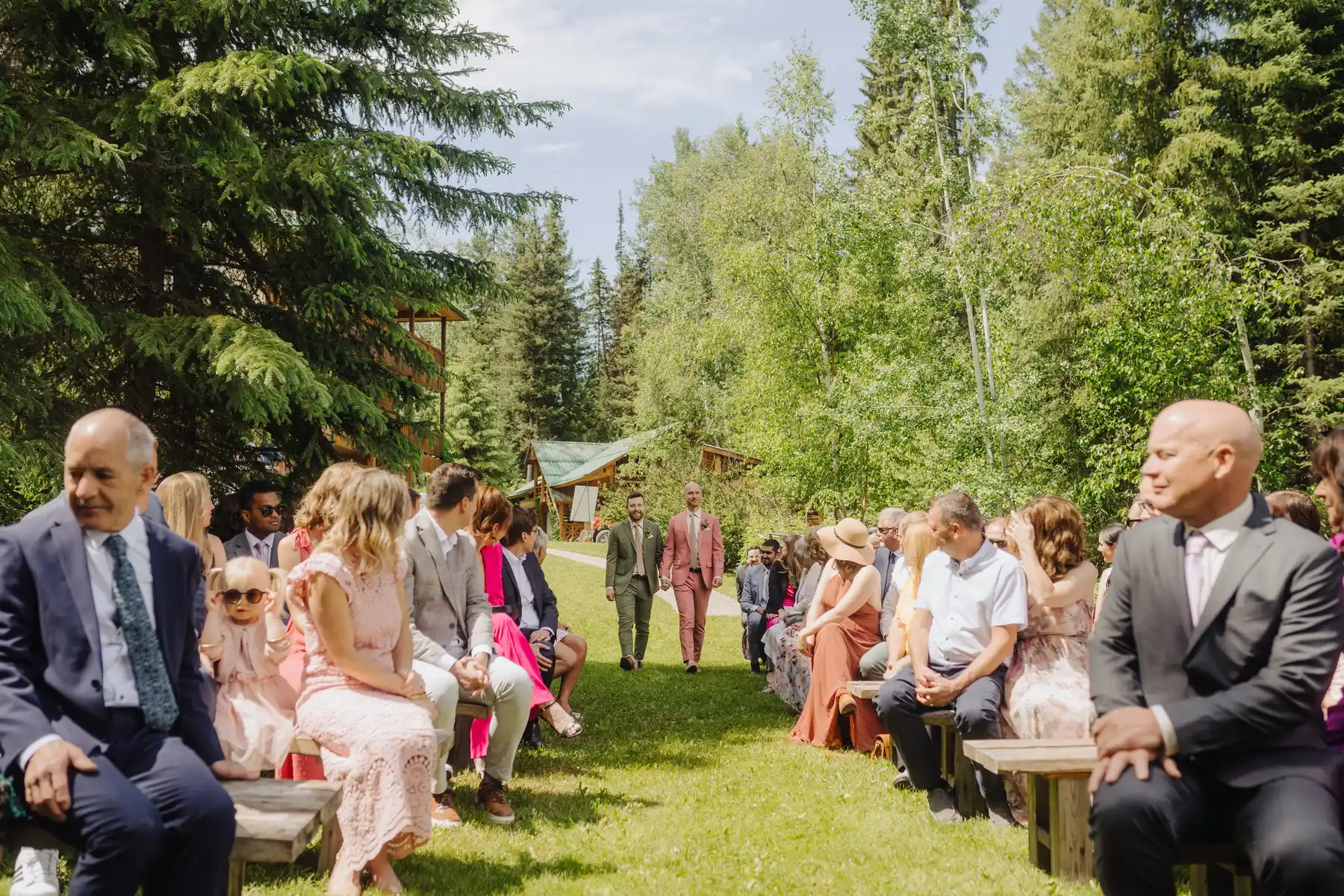 Trent and Cameron Harris-McCoy walk down the outdoor aisle at The Hillside Lodge & Chalets in Golden, BC, Canada.