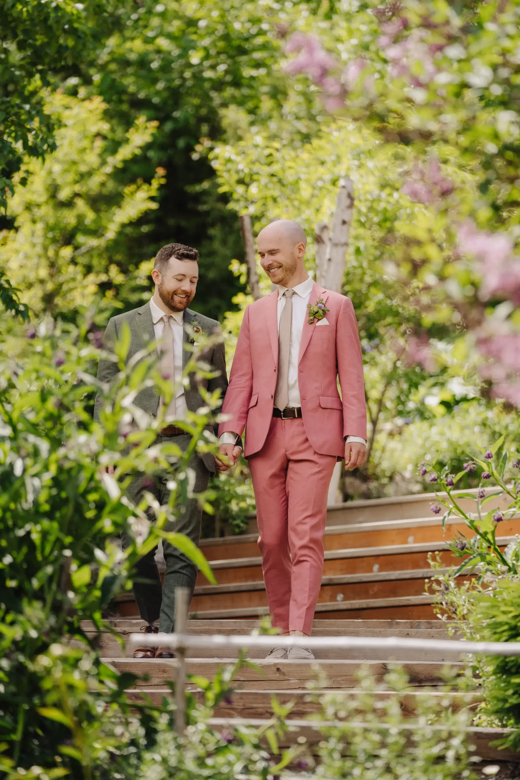 Trent and Cameron Harris-McCoy hold hands walking down garden steps at The Hillside Lodge & Chalets in Golden, BC.