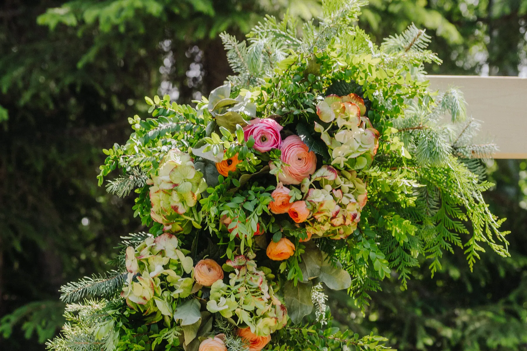 Lush floral arrangement with pink and orange ranunculus and green hydrangeas at The Hillside Lodge & Chalets in Golden, BC.
