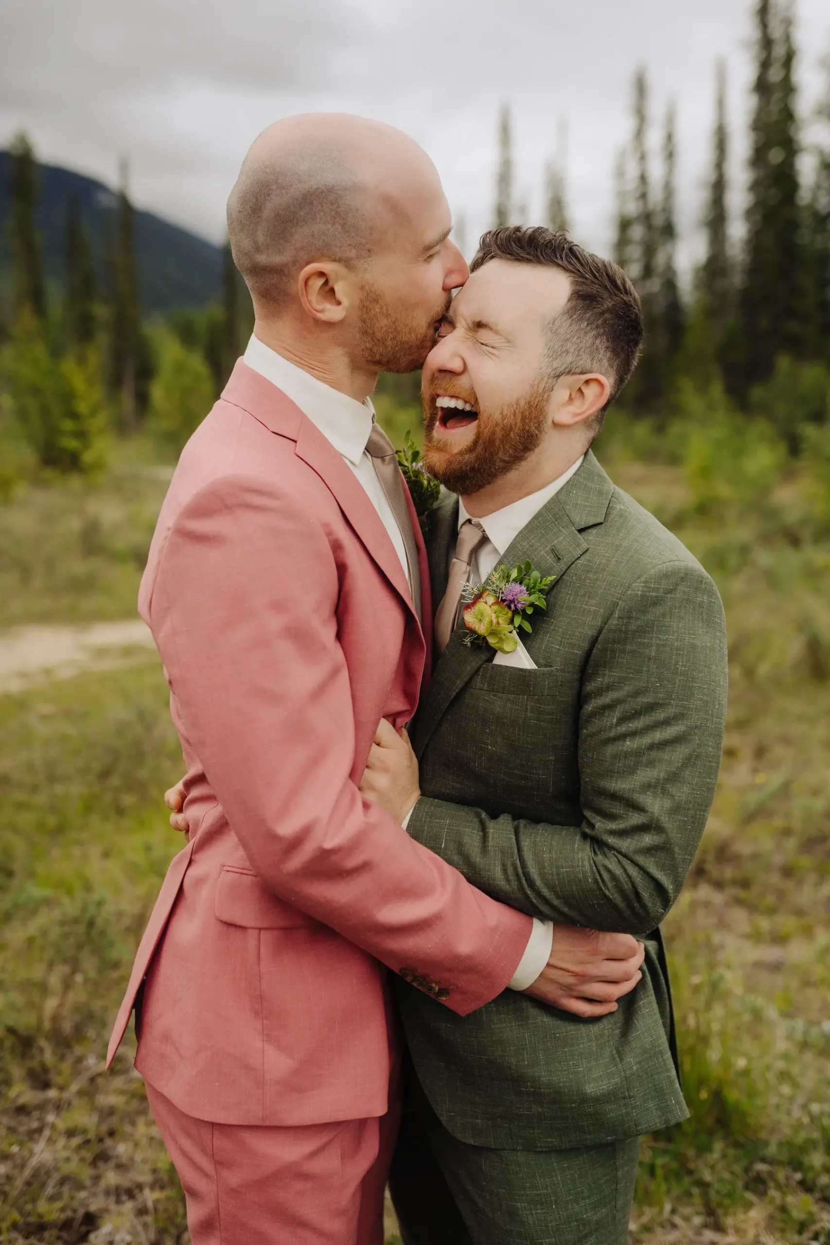 Trent and Cameron Harris-McCoy laugh and embrace in colorful suits at The Hillside Lodge & Chalets in Golden, BC.
