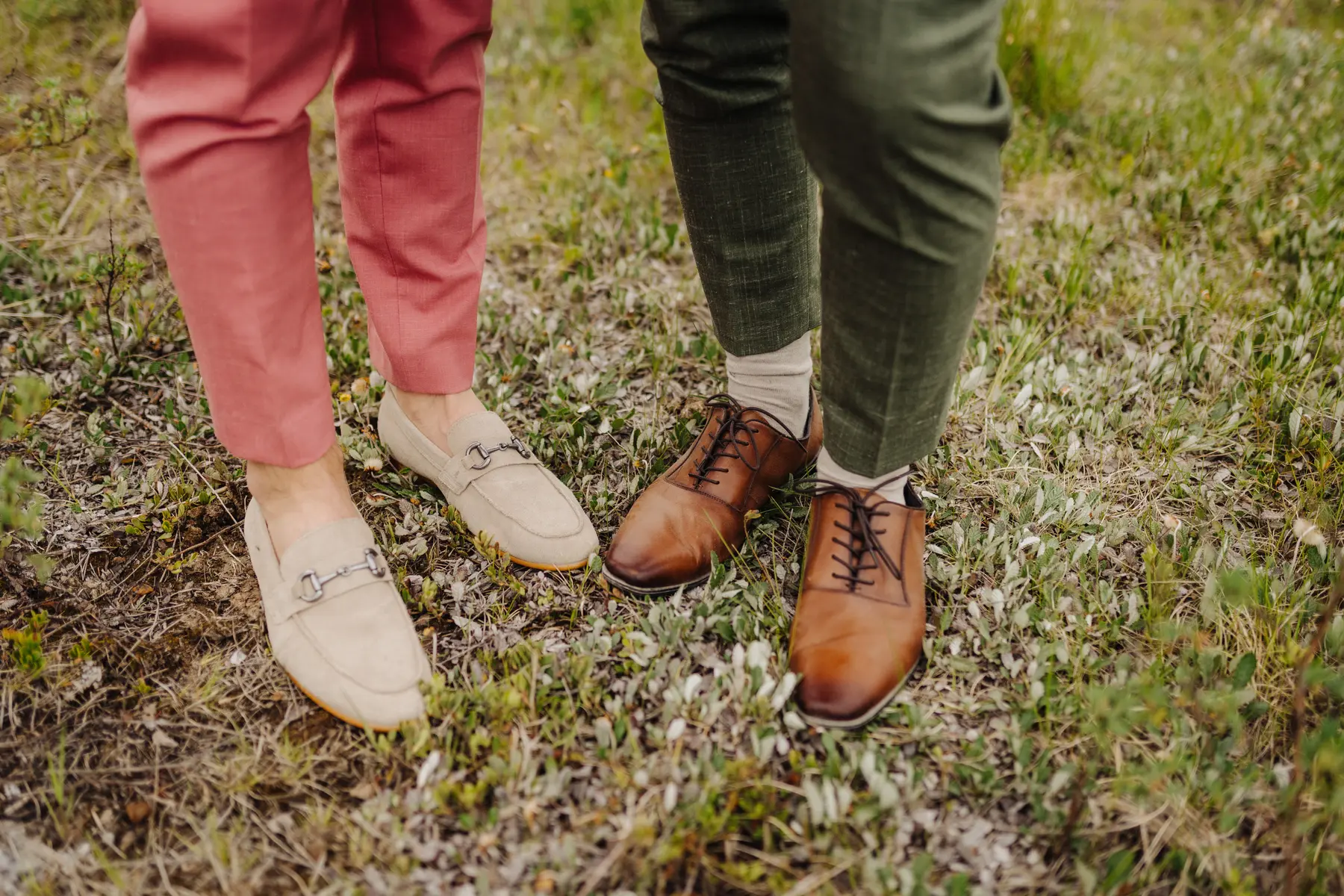 Close-up of Trent and Cameron Harris-McCoy's wedding shoes — beige loafers and brown lace-ups — on grassy ground at The Hillside Lodge & Chalets.