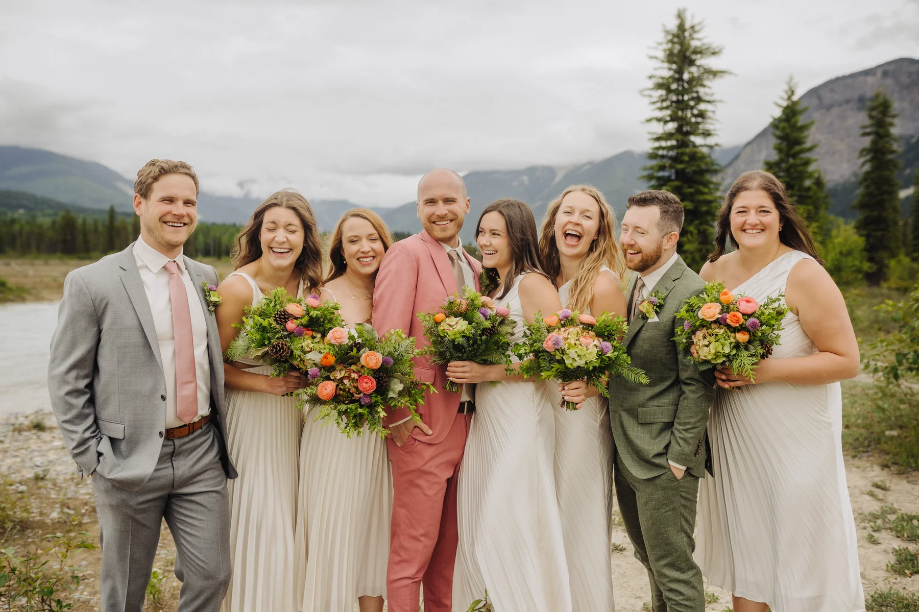 Trent and Cameron Harris-McCoy laugh with their wedding party outdoors at The Hillside Lodge & Chalets in Golden, BC.
