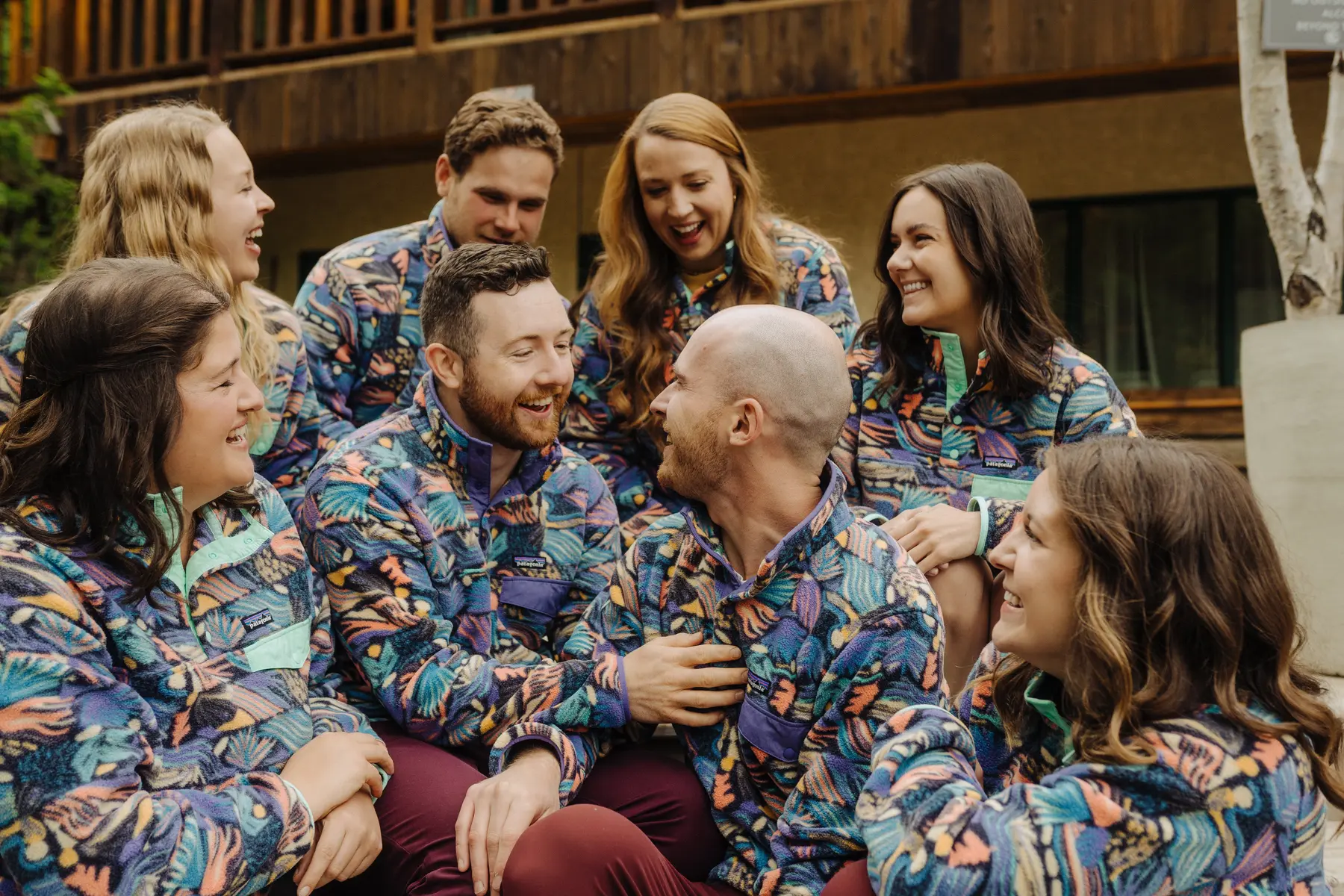 Trent and Cameron Harris-McCoy laugh with their wedding party in matching Patagonia fleeces at The Hillside Lodge in Golden, BC.