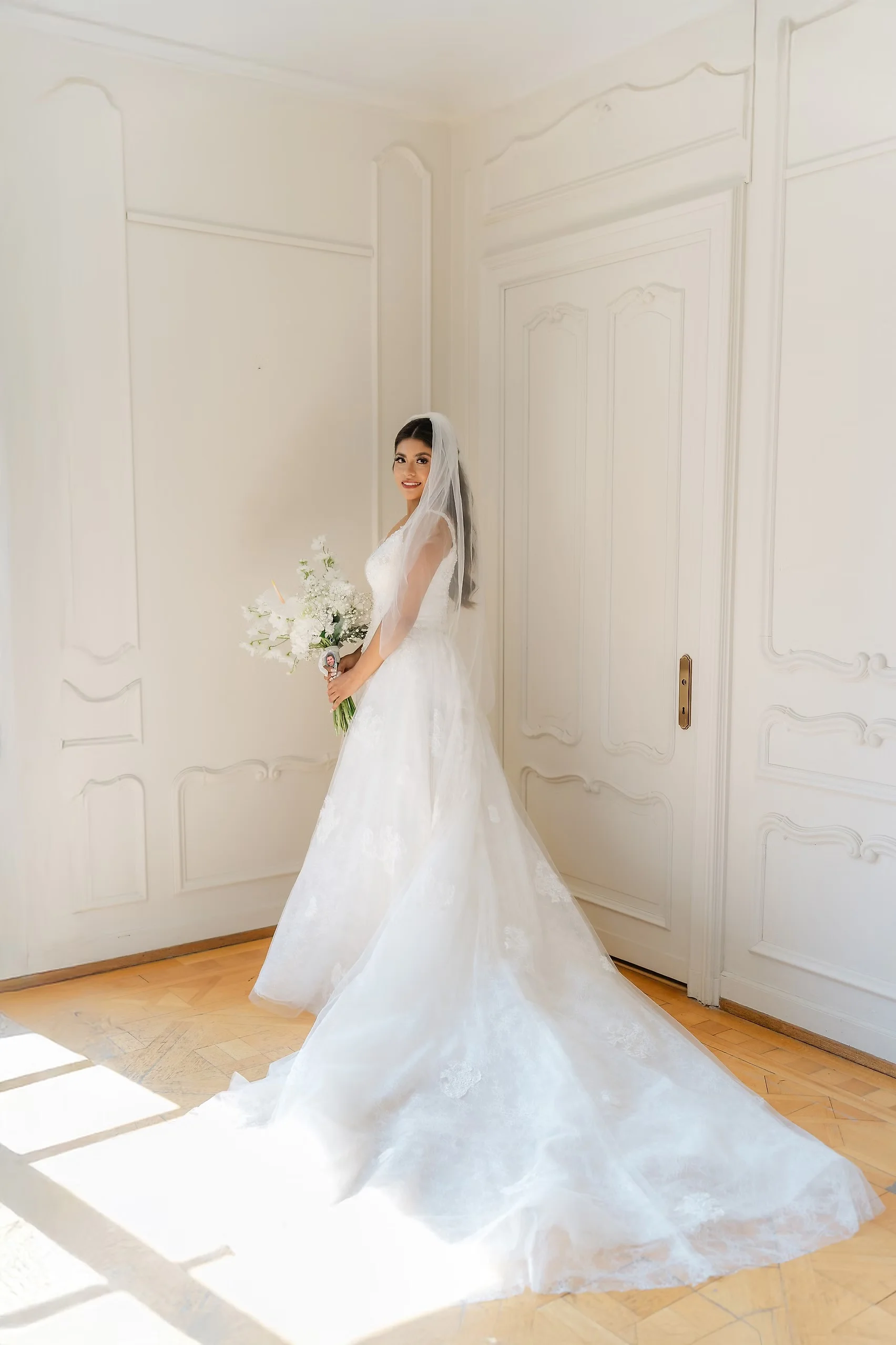 Bride Ashley Rodriguez-Vargas poses in a white ballgown and veil holding a white bouquet inside Villa Emden on Brissago Island.