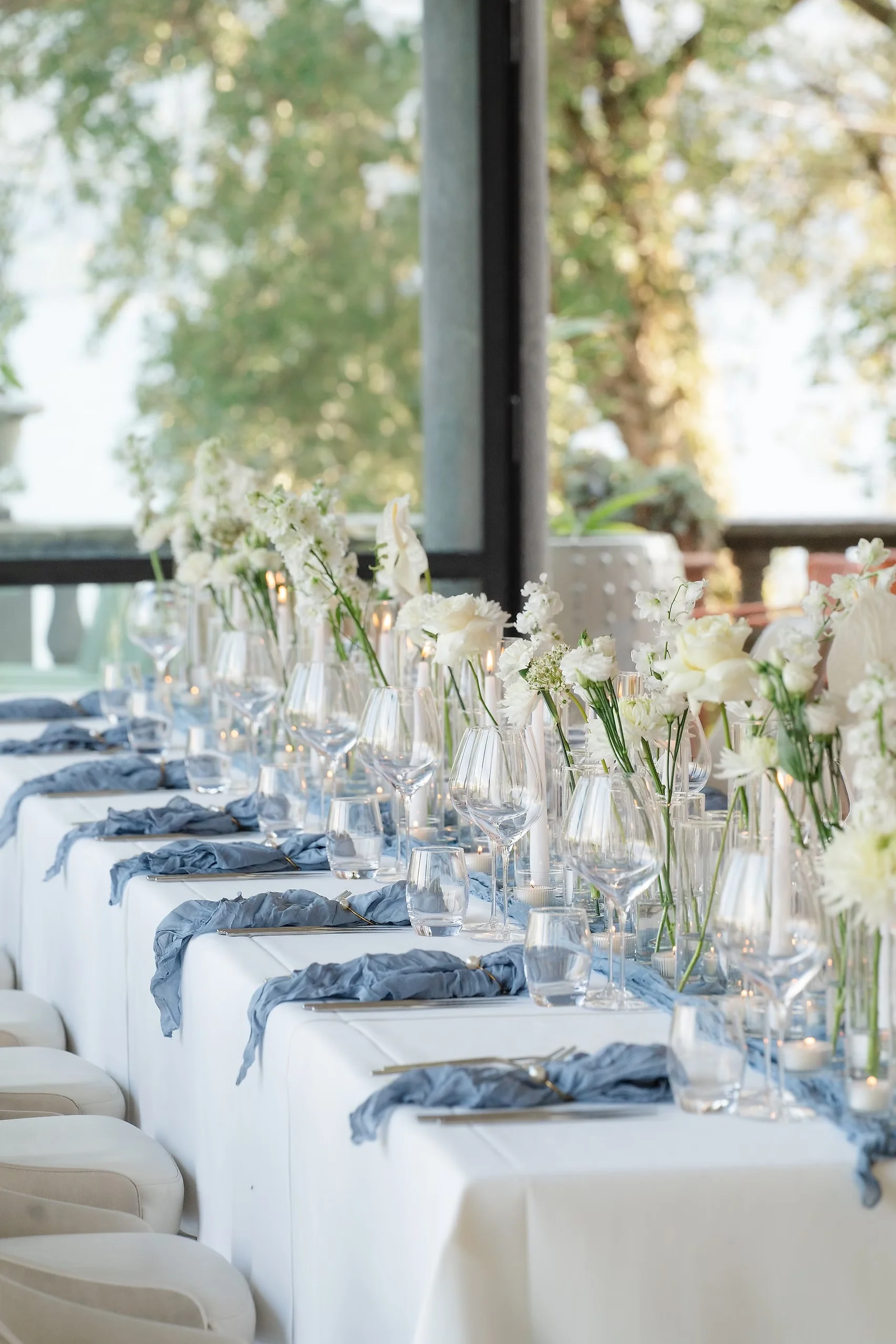 Elegant reception tablescape at Villa Emden on Brissago Island, Switzerland, with white florals and dusty blue napkins.