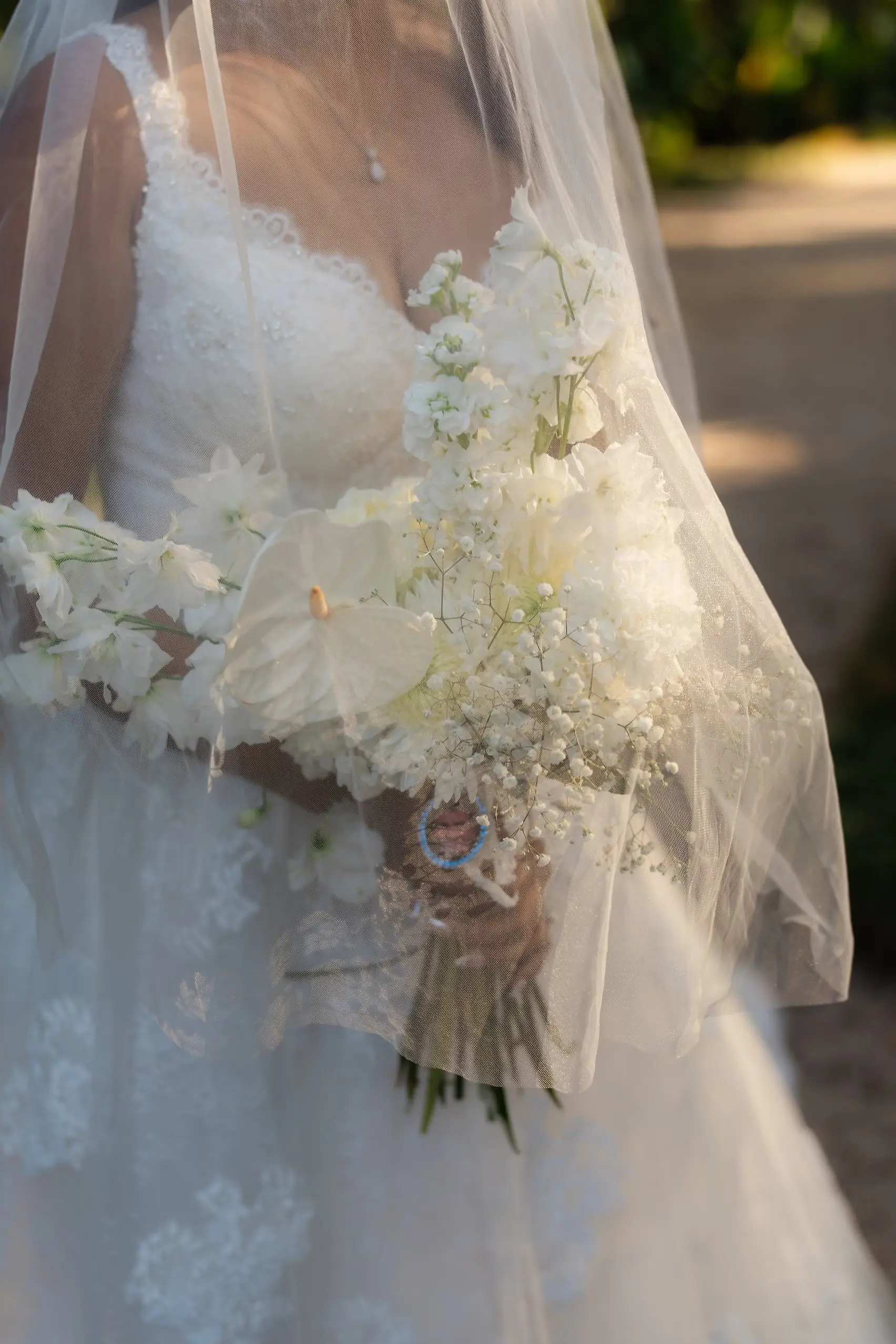 Bride Dionne Vargas holds a white bouquet of anthuriums and baby's breath, veil draped over at Villa Emden.