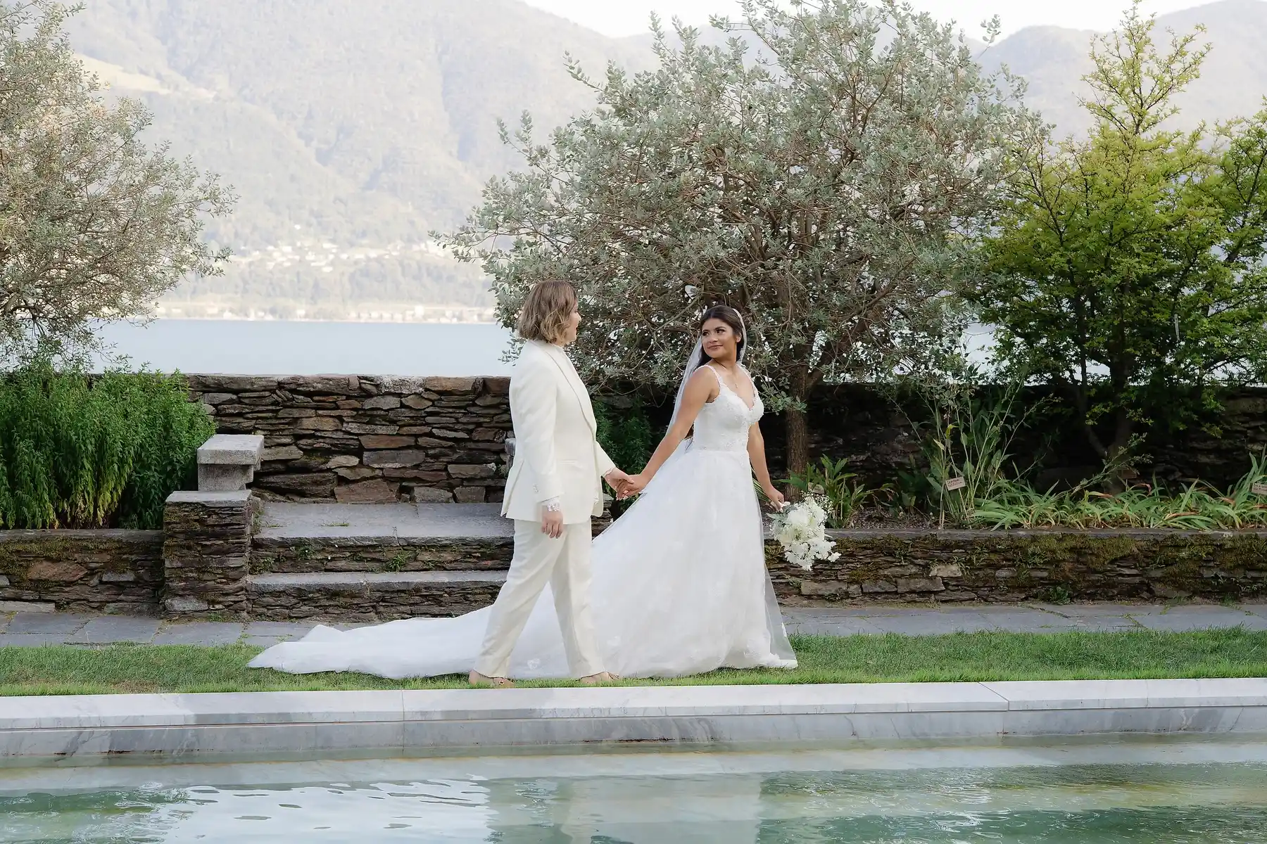 Ashley and Dionne Vargas walk hand in hand beside a reflecting pool at Villa Emden on Brissago Island, Switzerland.